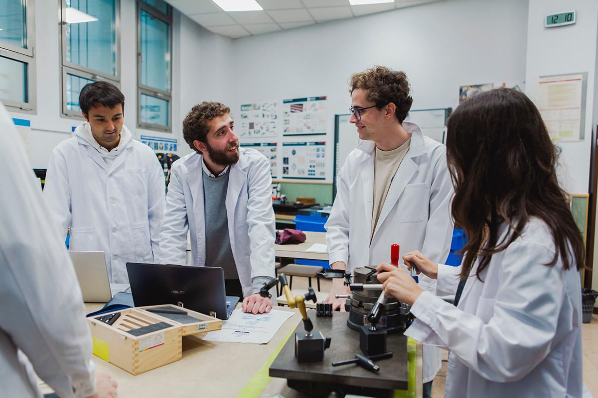 Un grupo de estudiantes en un laboratorio discutiendo sobre un proyecto mientras trabajan en una mesa con varios instrumentos y herramientas.