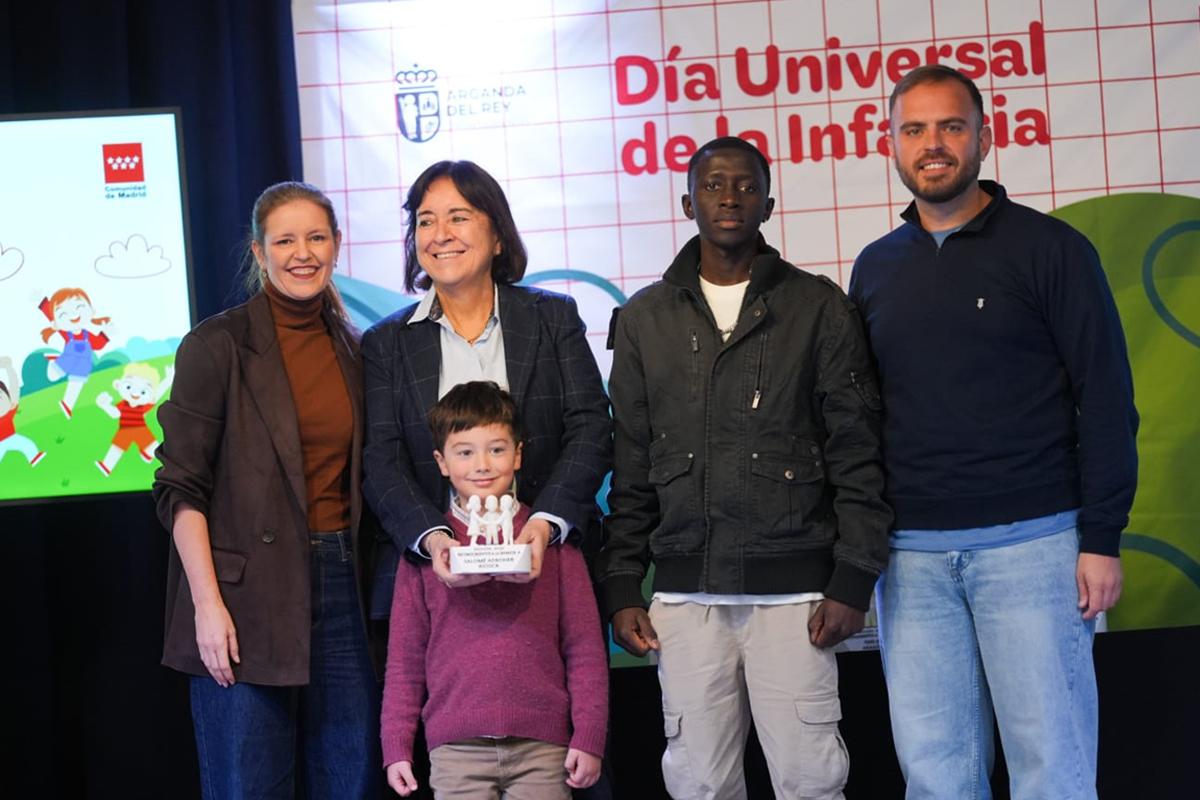 Un grupo de cinco personas sostiene un trofeo durante un evento por el Día Universal de la Infancia.