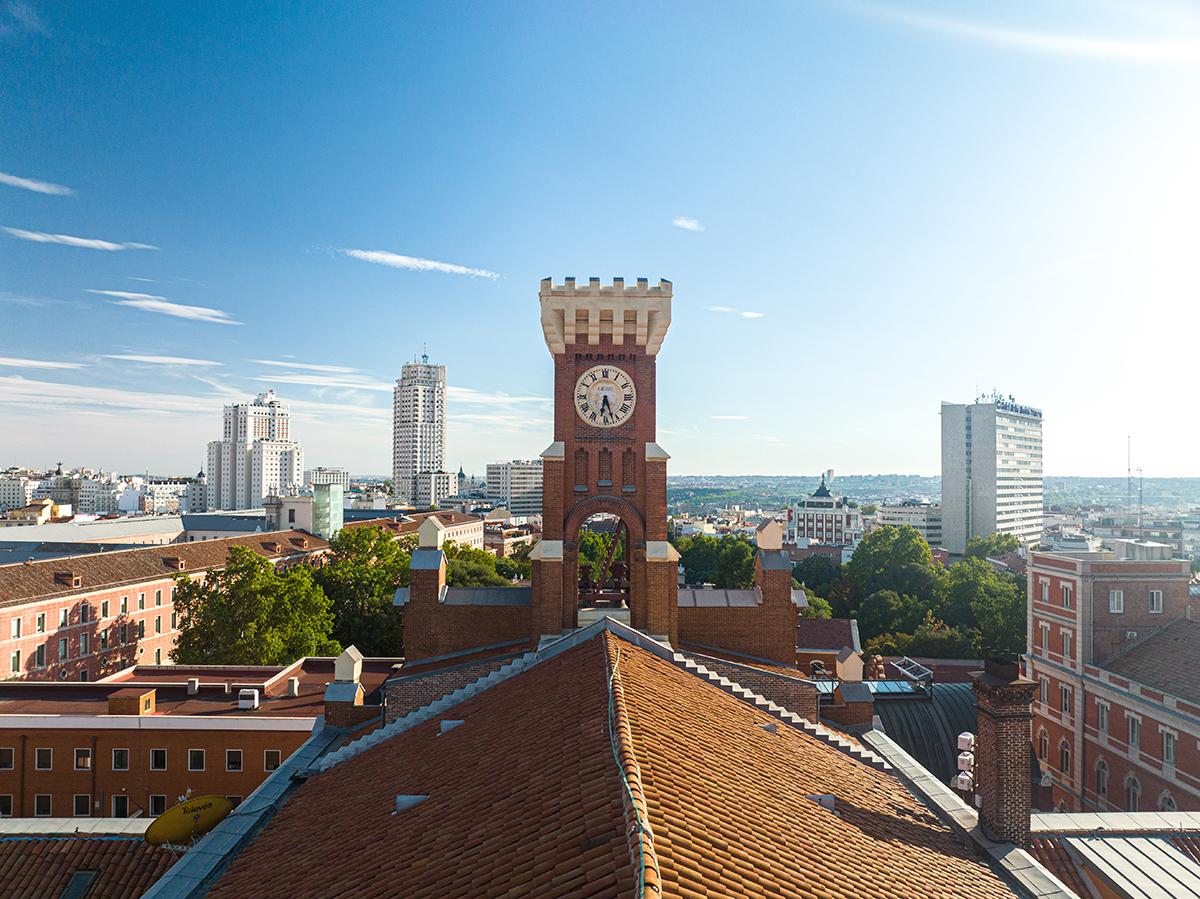 Vista panorámica de una ciudad con un reloj prominente y edificios modernos al fondo.