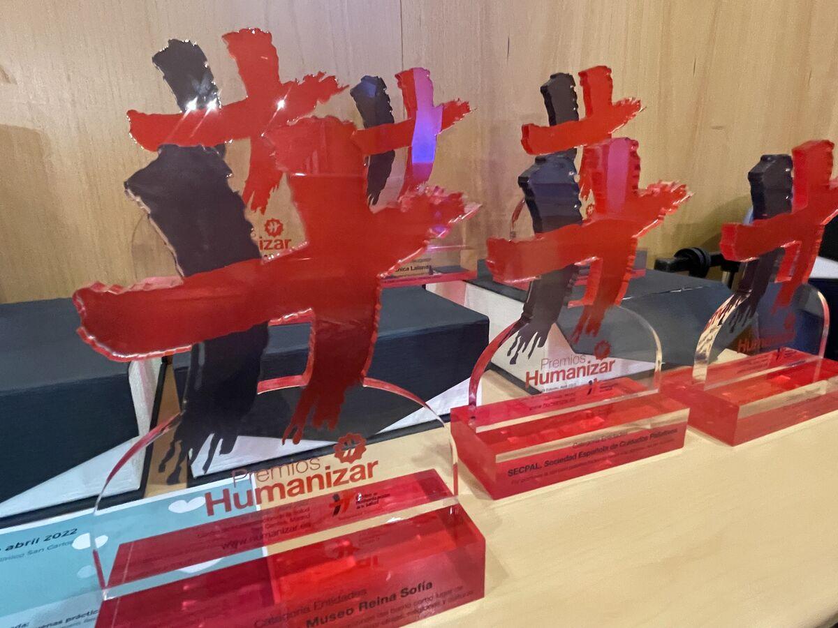 A collection of red silhouette trophies on clear bases displayed on a wooden shelf.