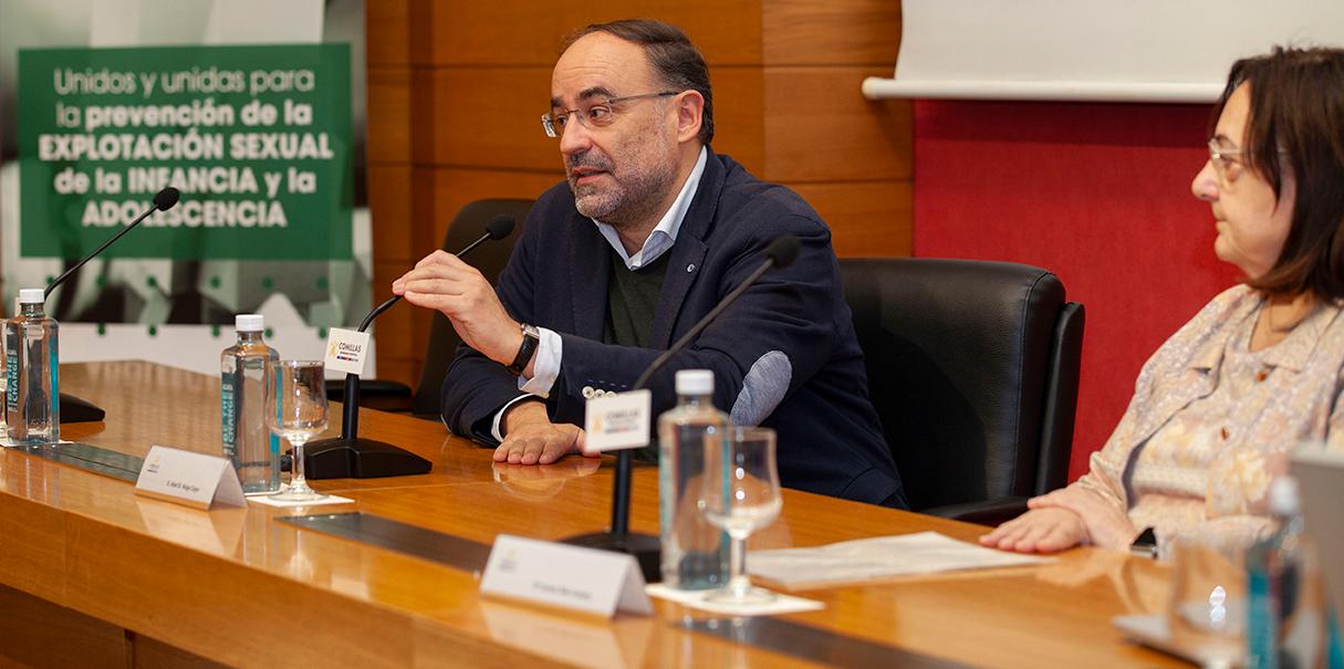 Un hombre gesticula mientras habla en un panel de discusión sobre la prevención de la explotación sexual infantil, acompañado de otros participantes.