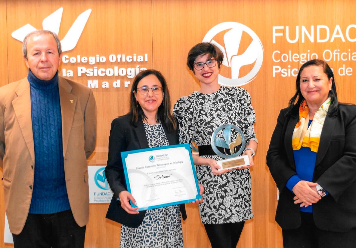 Cuatro personas posan con un premio y un certificado en un evento del Colegio Oficial de la Psicología.