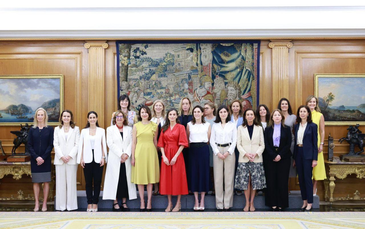 Fotografía grupal de mujeres en un evento formal con retratos en un entorno elegante.