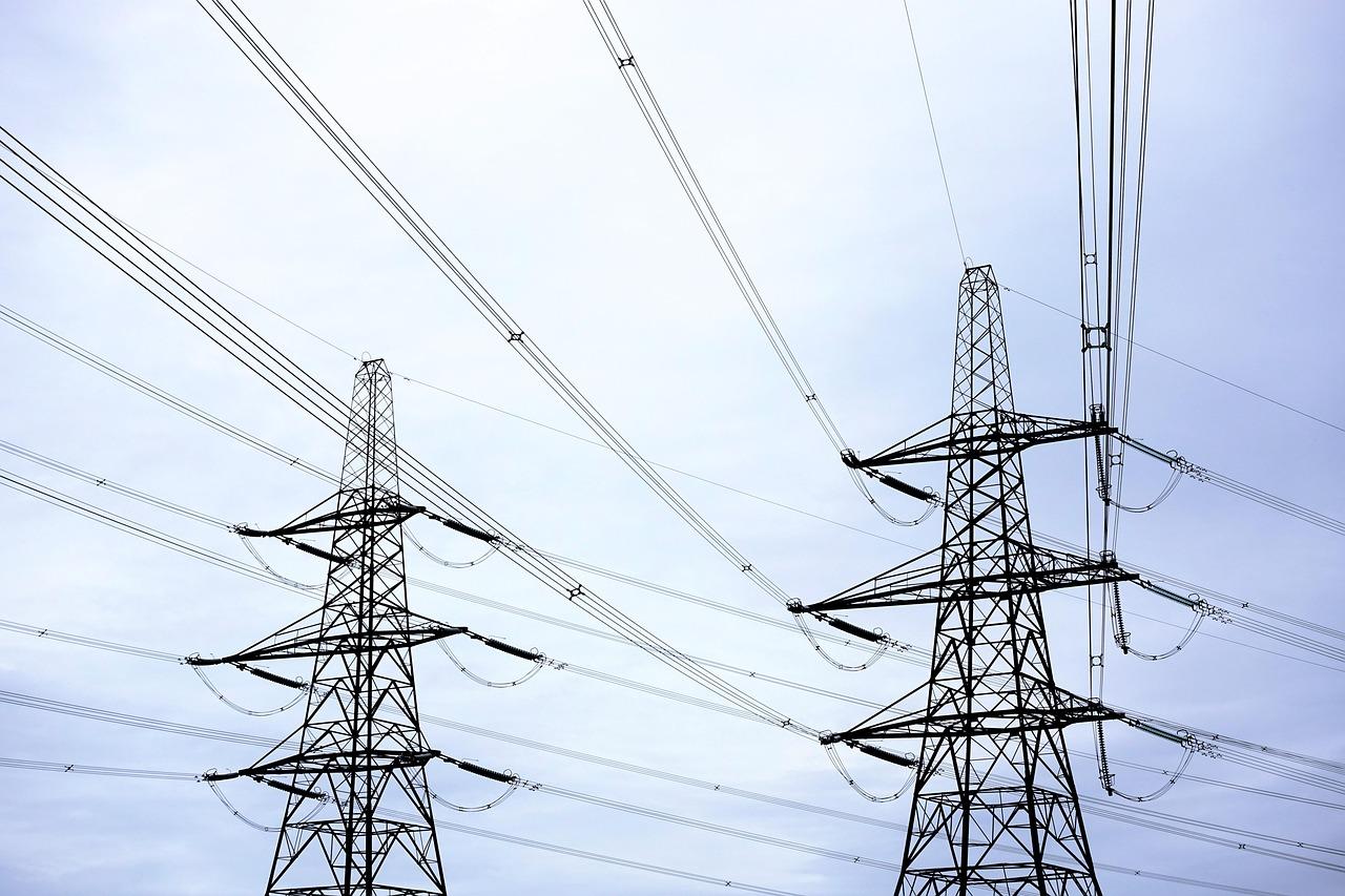 Imagen de torres de transmisión eléctrica bajo un cielo nublado.