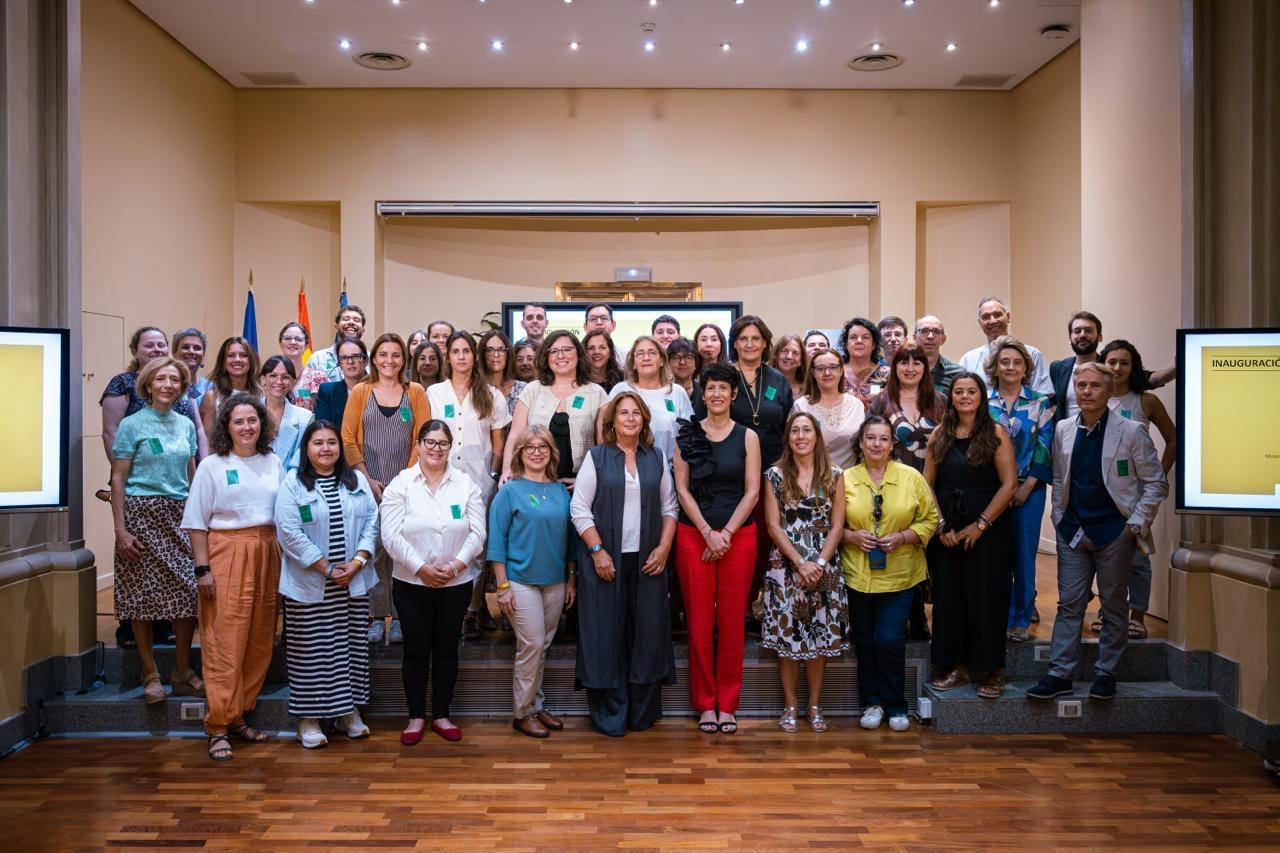 Un grupo grande de personas se reúne en un evento, posando en el escenario con semblantes sonrientes.