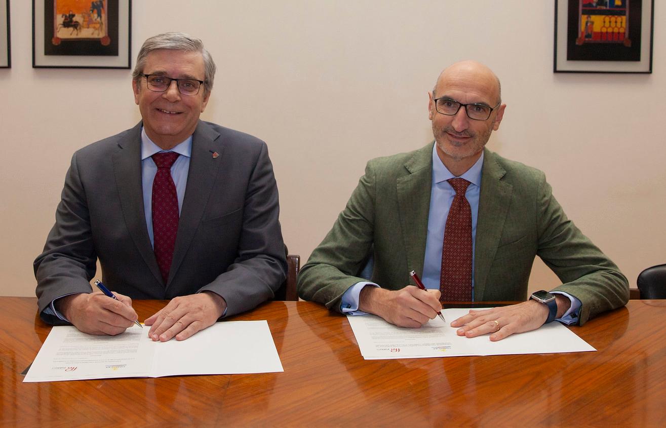 Dos hombres sentados a una mesa firmando documentos en una oficina.