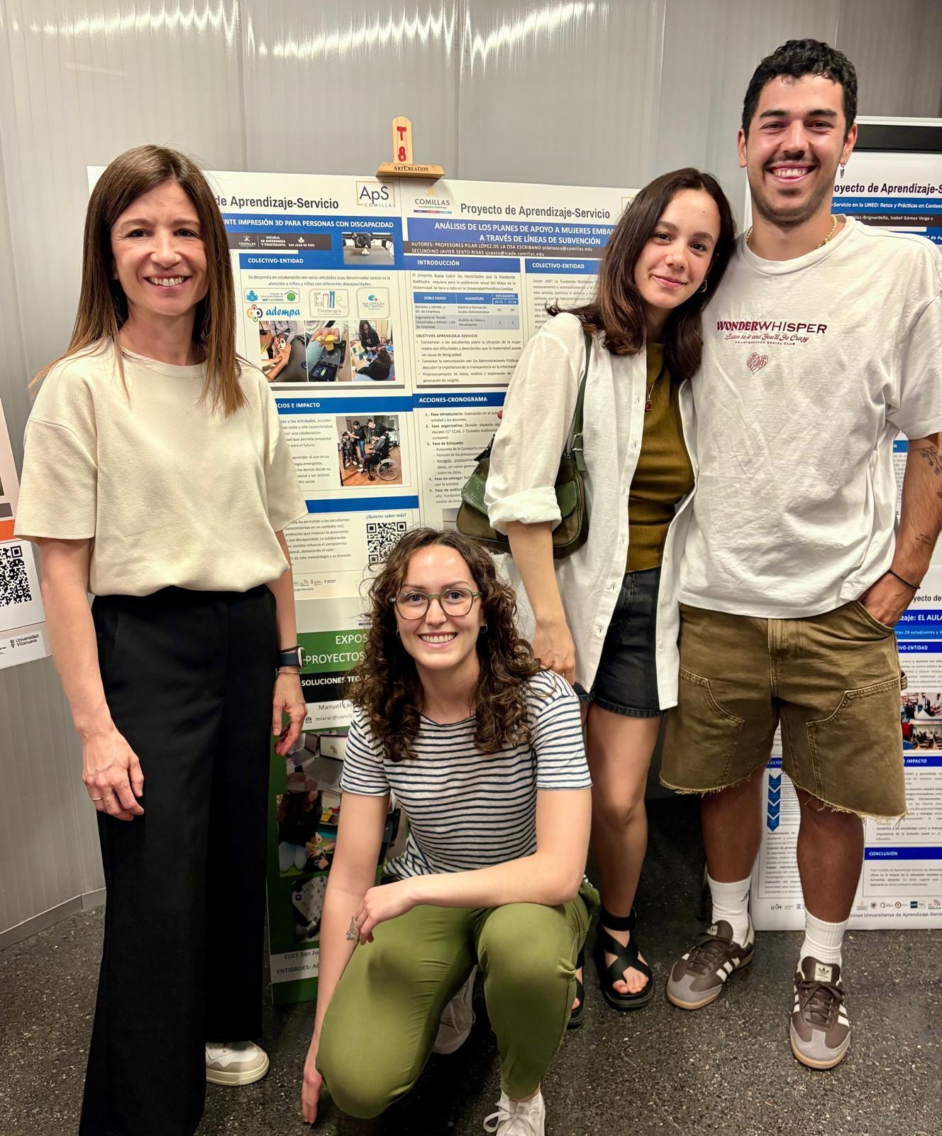 Un grupo de cuatro personas sonríen frente a un panel informativo sobre un proyecto de aprendizaje servicio.