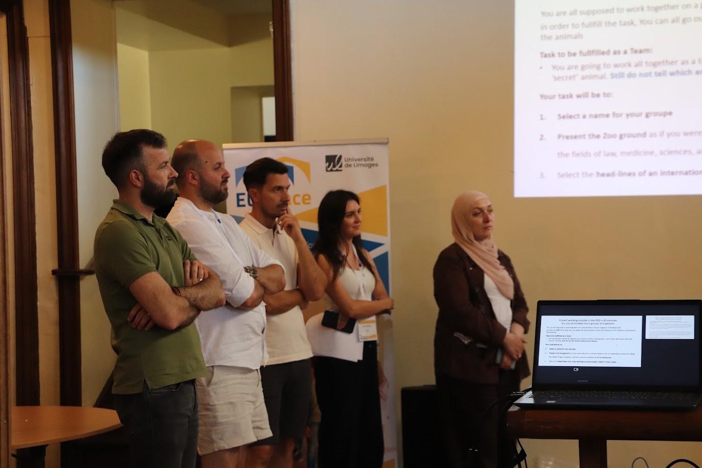 Un grupo de personas está de pie frente a una presentación en una sala de conferencias.