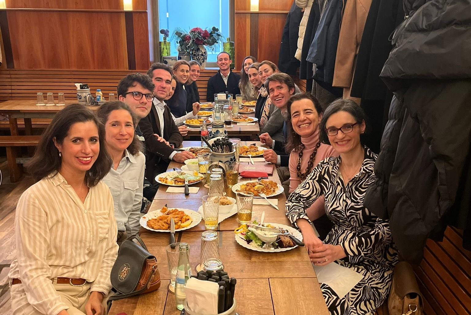 Una grupo de personas disfrutando de una comida en una mesa larga.