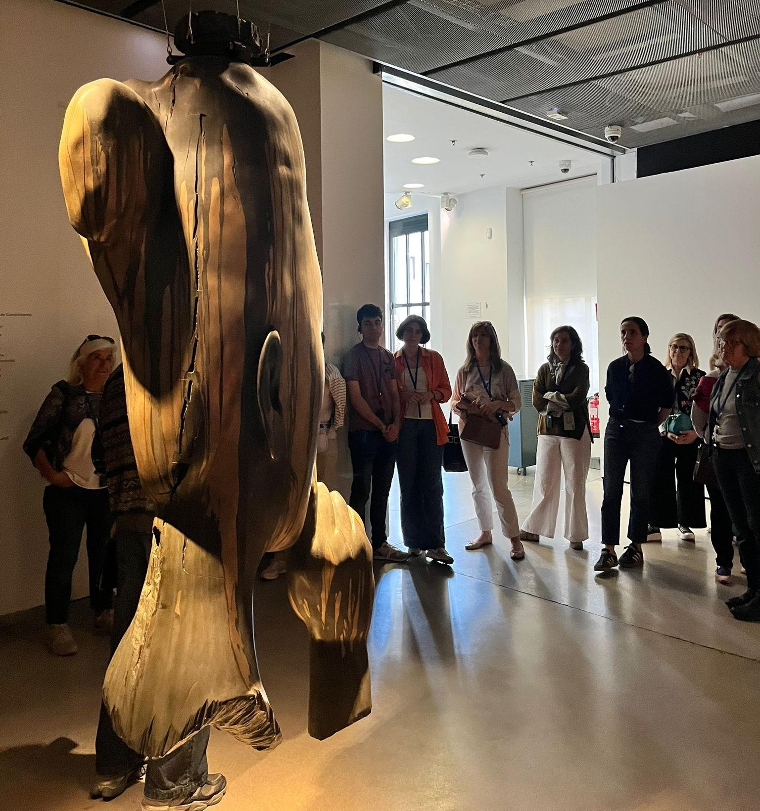 Un grupo de personas observa una escultura en una galería de arte.