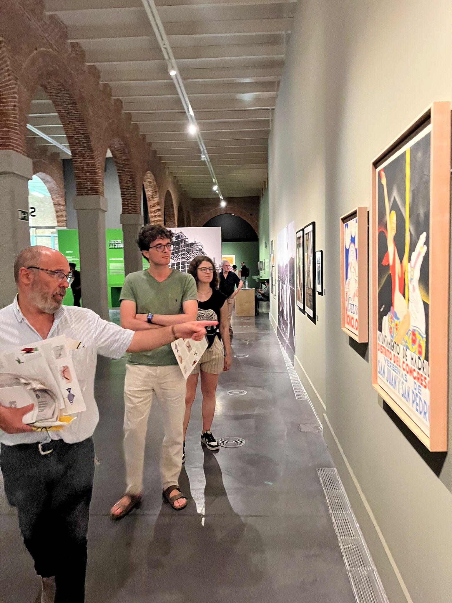 Un grupo de personas observa obras de arte en una galería moderna.