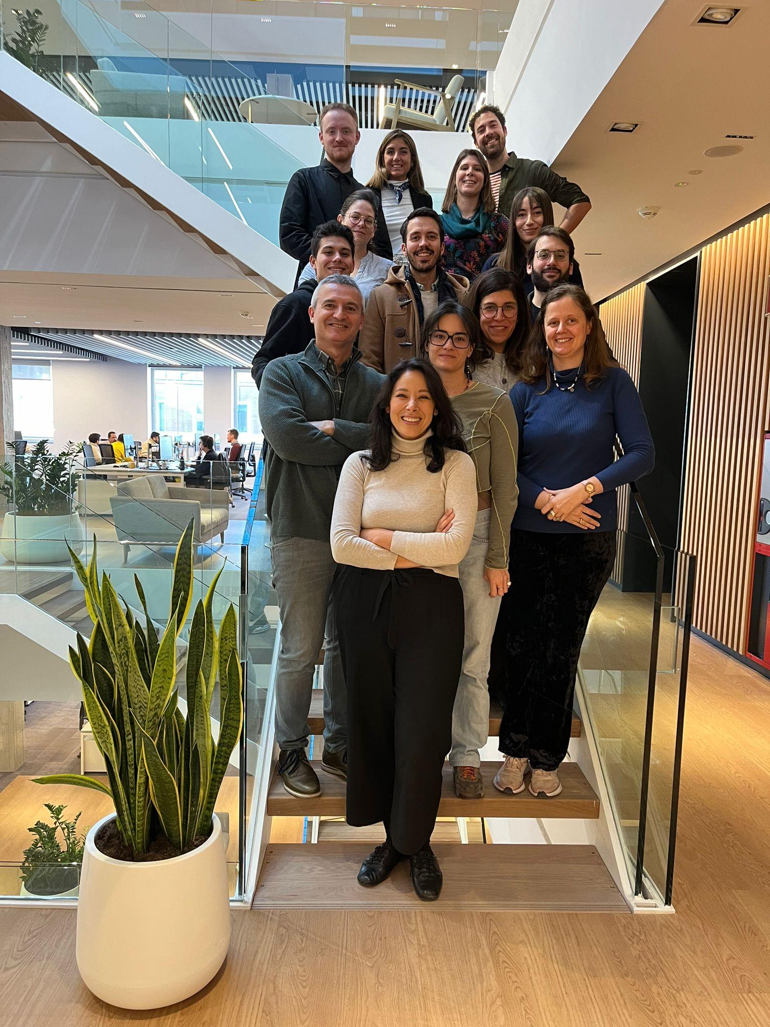 Un grupo de personas sonriendo para la foto en una oficina moderna.