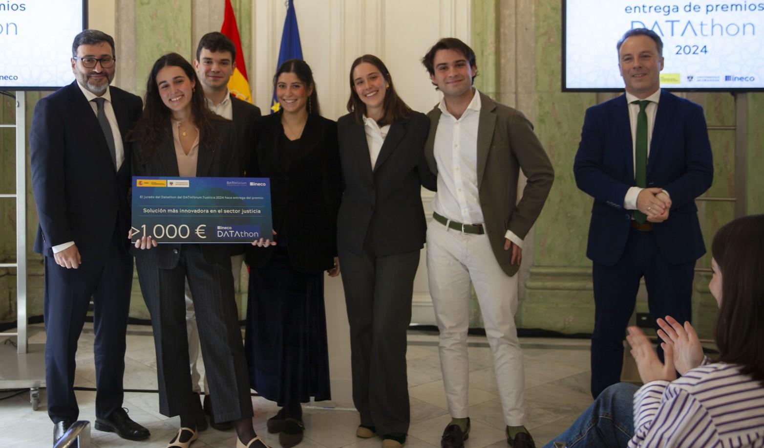 Un grupo de seis personas sonríe mientras sostienen un cheque en un evento de entrega de premios.