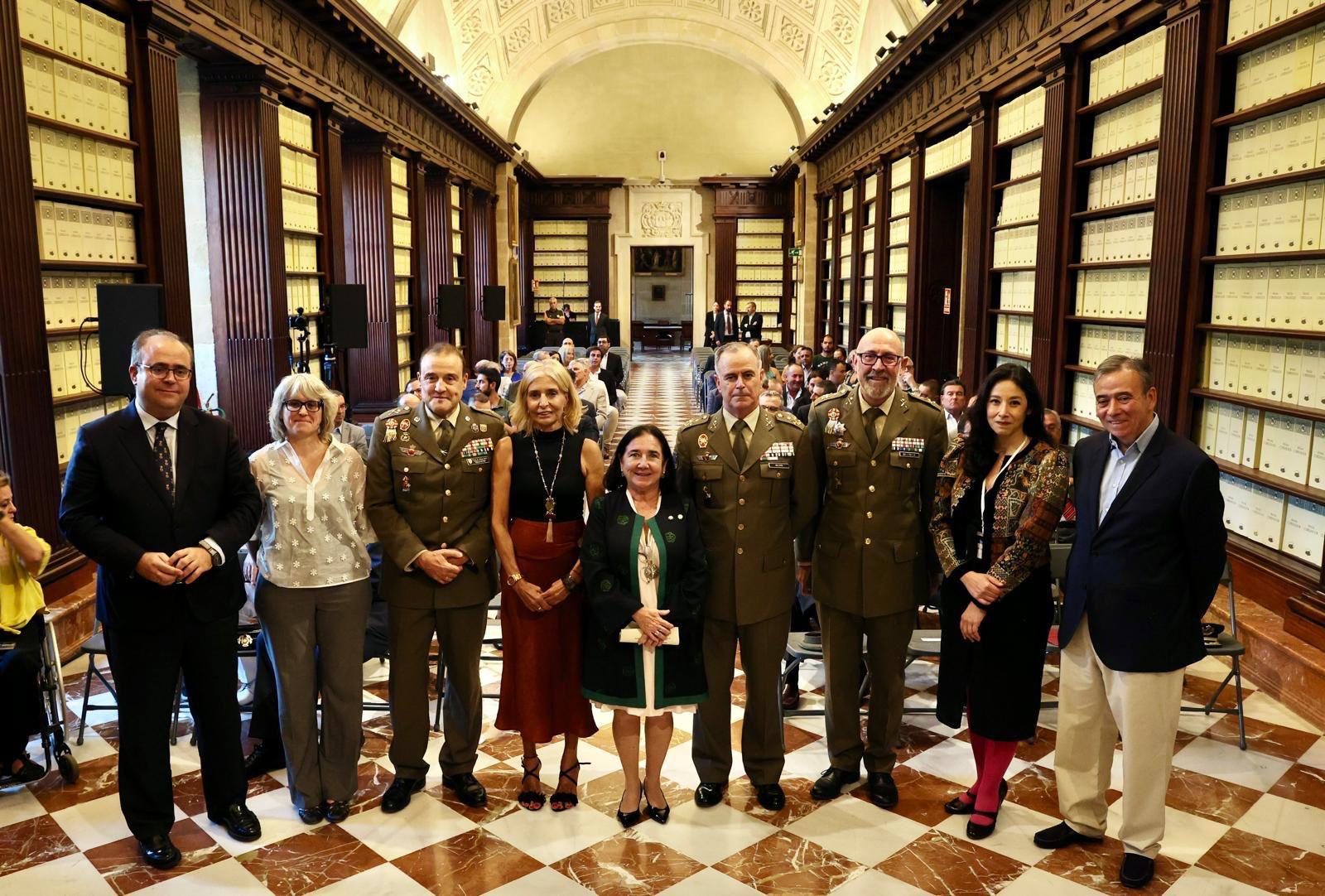 Un grupo de personas de pie en una biblioteca rodeados de estanterías con documentos.