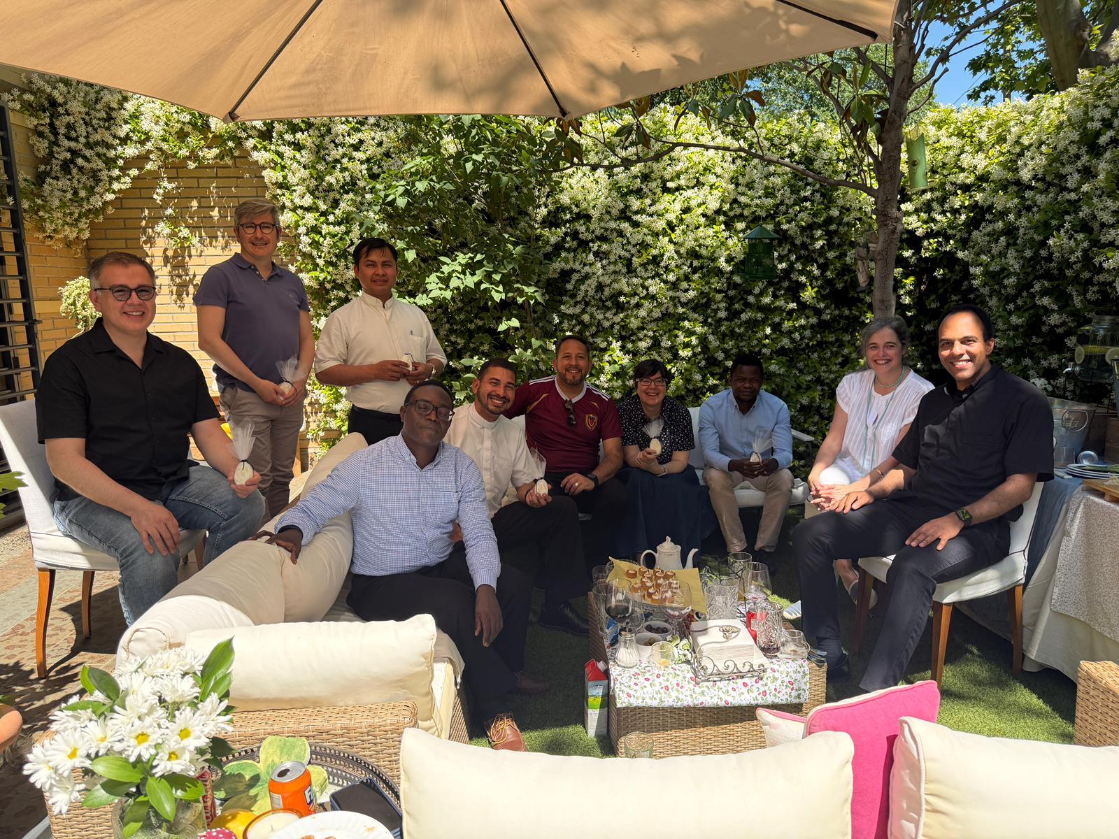 Un grupo de personas sonrientes se reúne en un agradable jardín al aire libre.