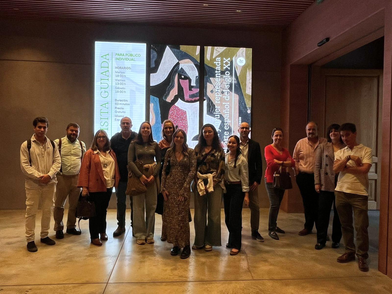 Un grupo de personas posando frente a una obra de arte en un museo.