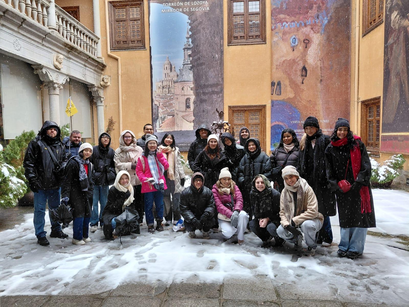 Un grupo de personas sonrientes posando en un paisaje nevado frente a un mural colorido.