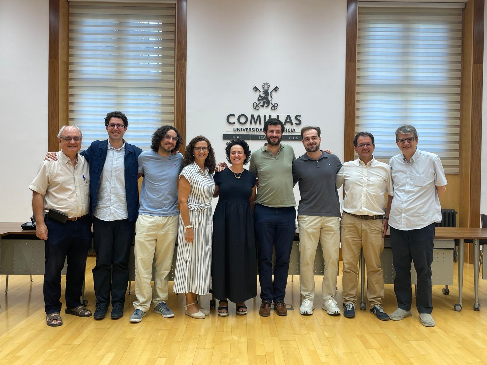 Un grupo de personas posando en una sala con un fondo institucional.