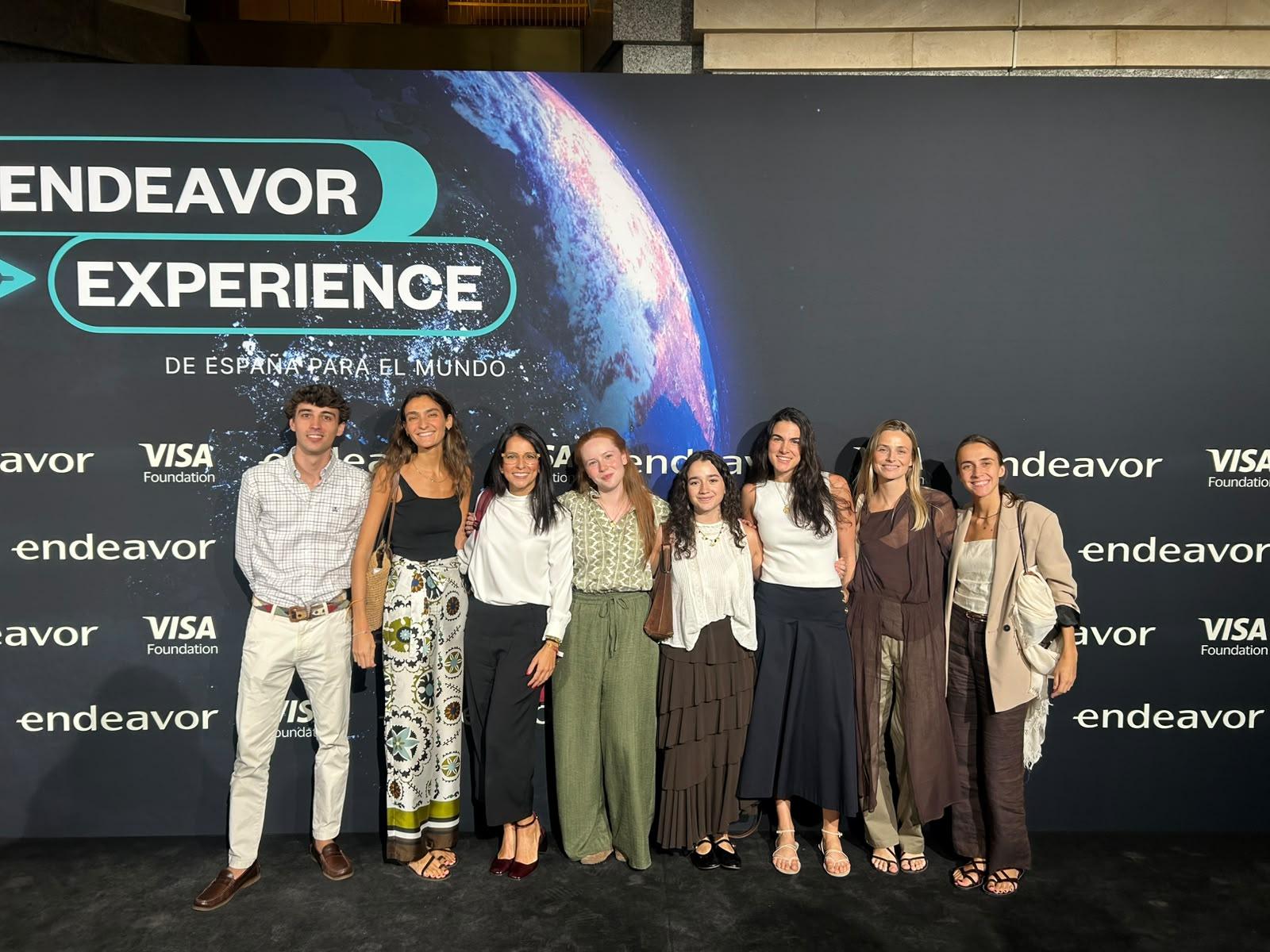 Grupo de personas posando en un evento de Endeavor en frente de una pantalla que muestra el logo de la organización.