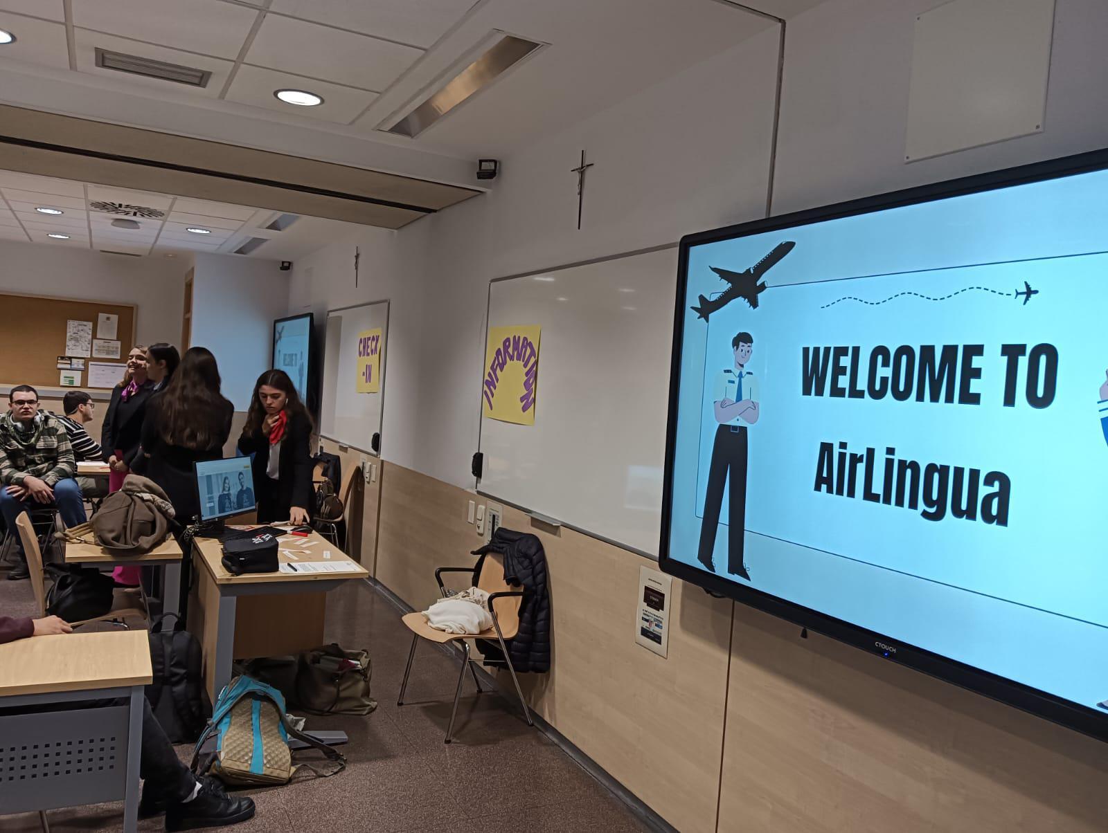 Un aula con un proyector que muestra un mensaje de bienvenida a 'AirLingua' y estudiantes interactuando.
