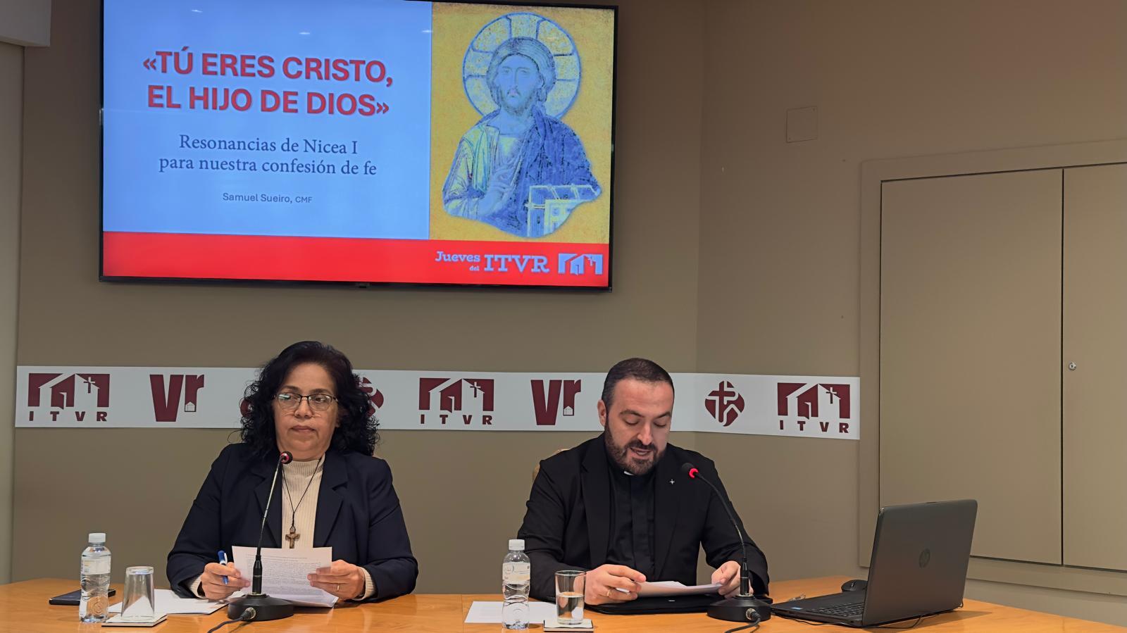 Dos personas presentan un evento relacionado con la fe cristiana en un entorno formal.