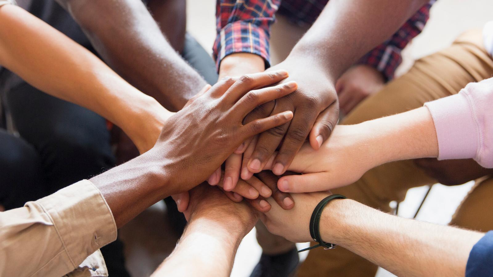Un grupo de manos unidas en un gesto de cooperación y unidad.
