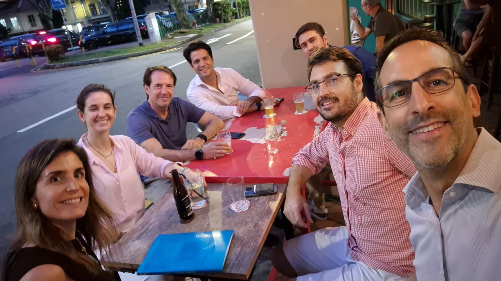 Un grupo de amigos sonríen y posan en un bar al aire libre durante la noche.
