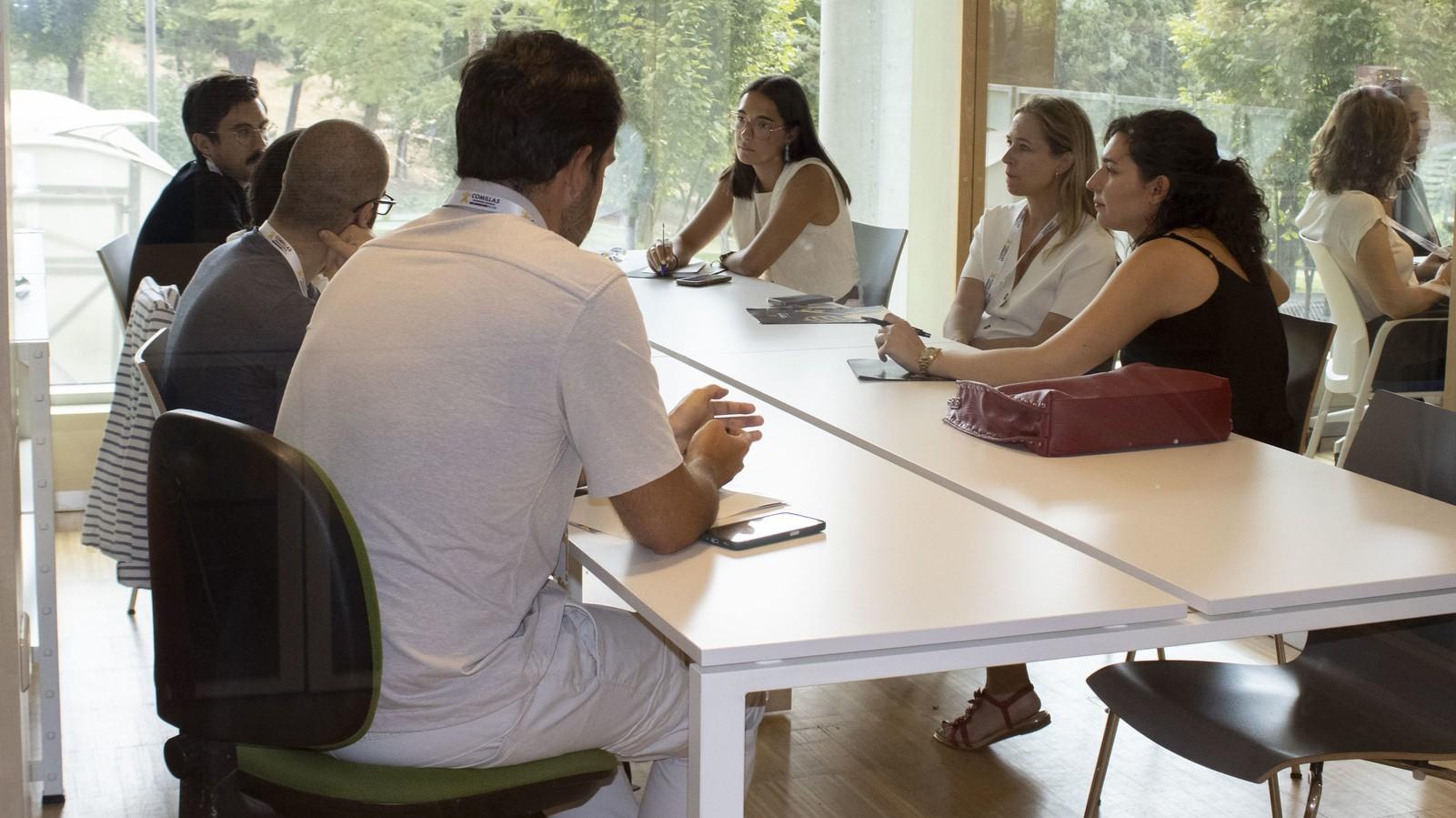 Un grupo de personas discutiendo alrededor de una mesa en un ambiente de oficina.