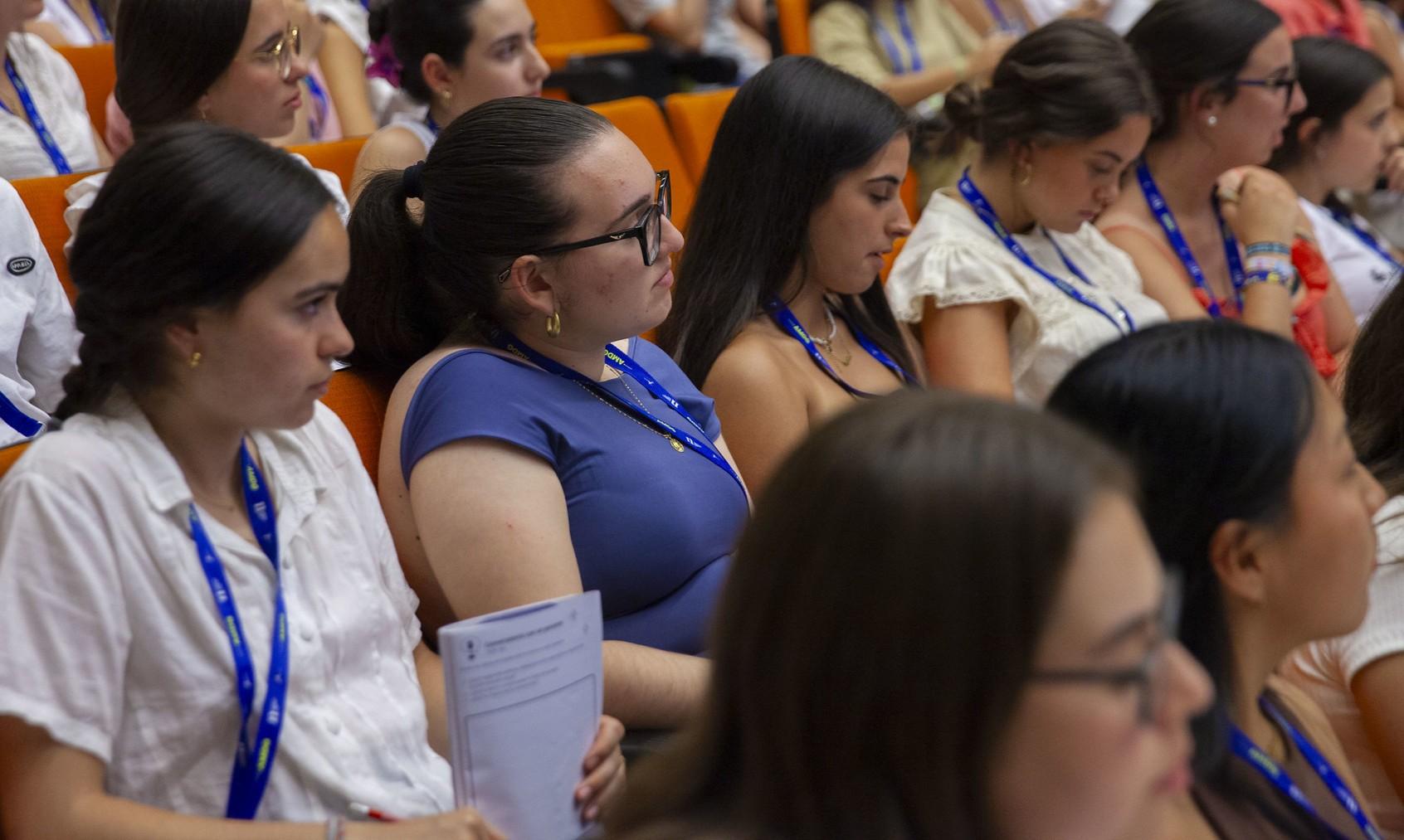 Un grupo de mujeres jóvenes en una conferencia, sentadas y escuchando atentamente.