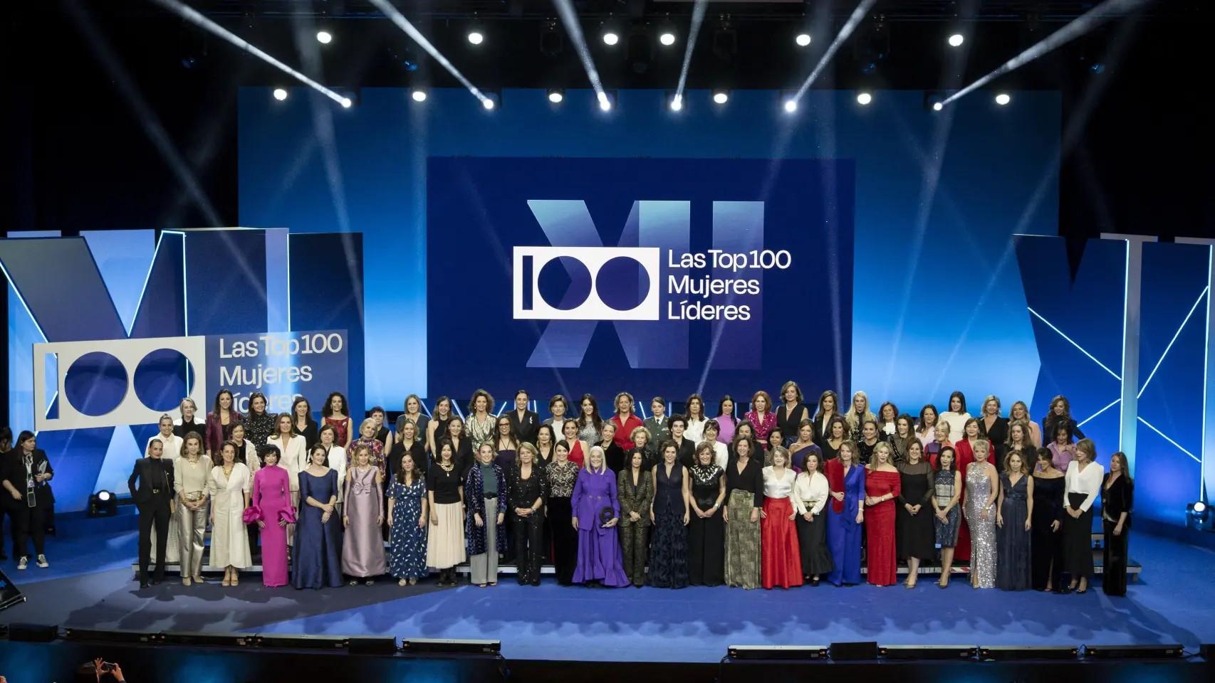 Evento que reúne a las 100 mujeres líderes en un escenario con un fondo azul y una gran pantalla.