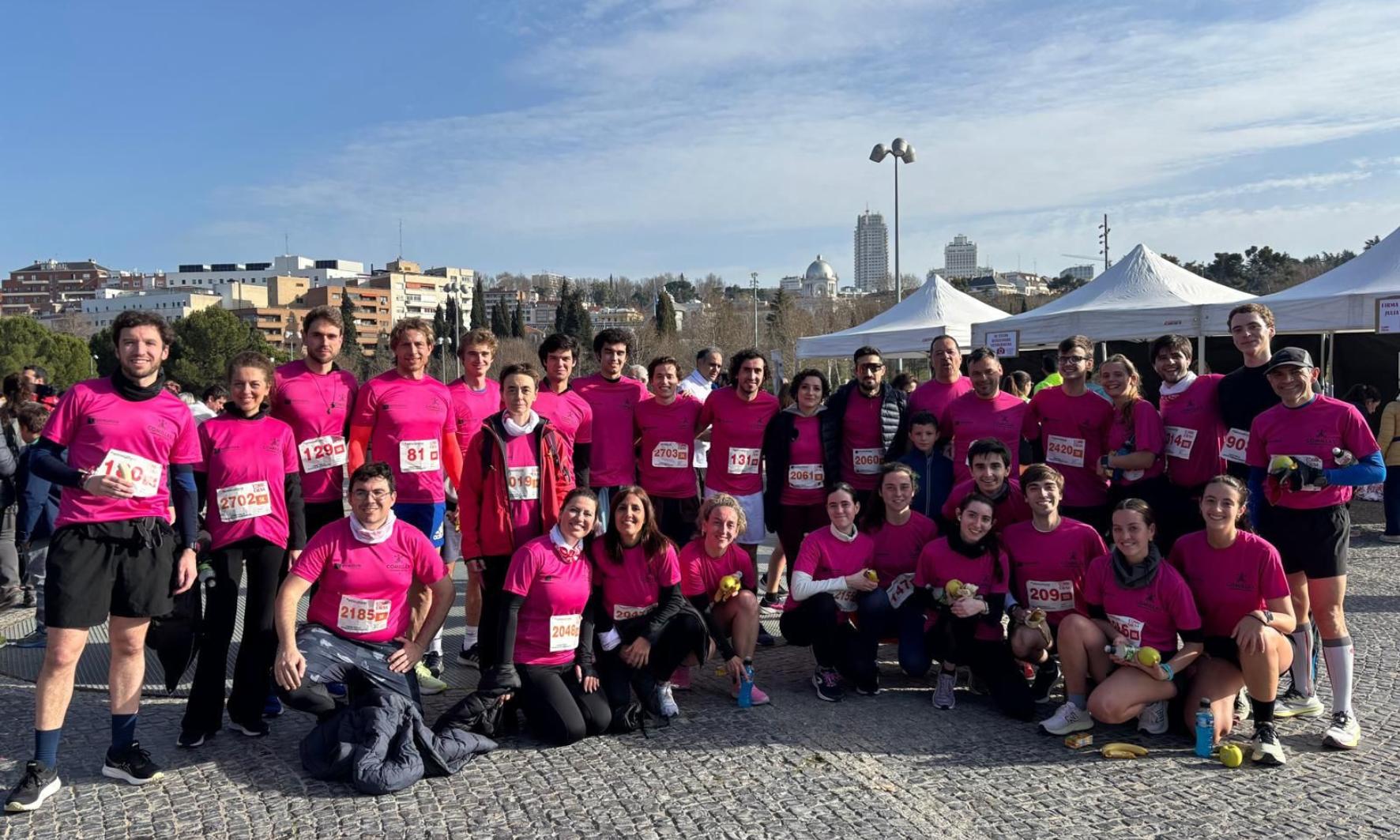 Un grupo de personas vestidas con camisetas rosas se preparan para una carrera al aire libre.