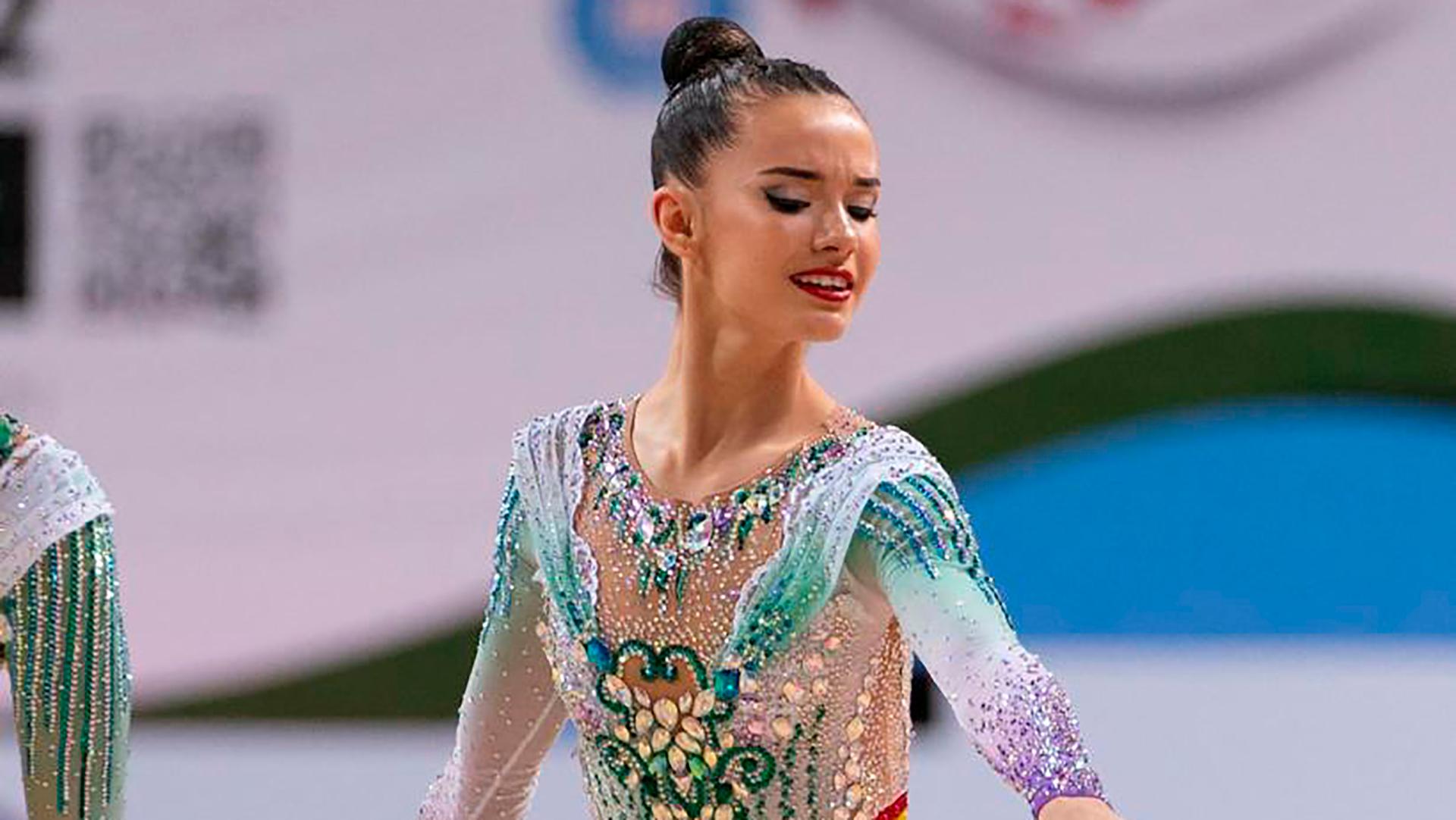 Una gimnasta rítmica en plena actuación con un hermoso traje brillante.