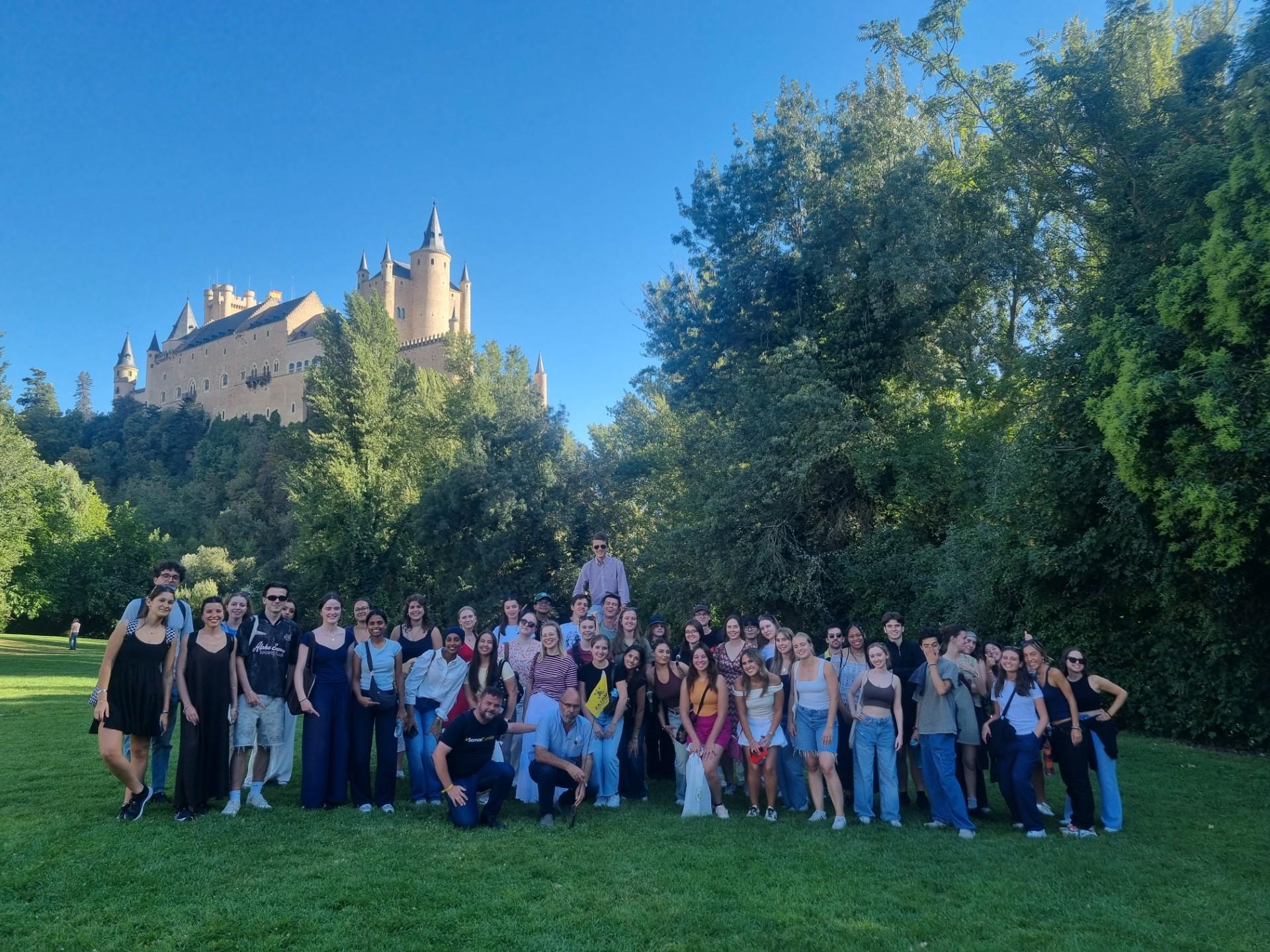 Un grupo de personas posando en un parque con un castillo al fondo.