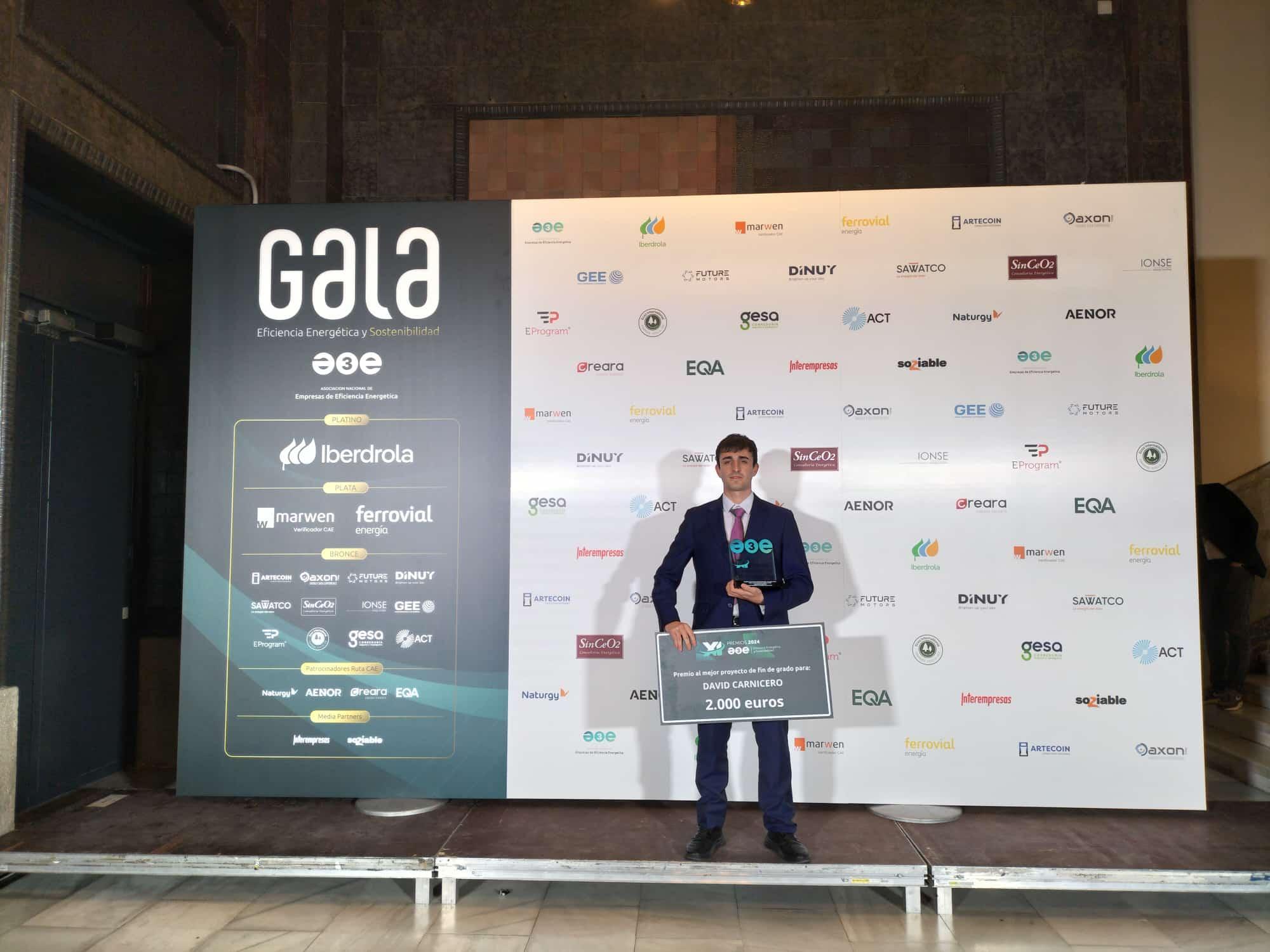 Un hombre vestido con traje posando frente a un pódium de premiación en un evento llamado GALA.