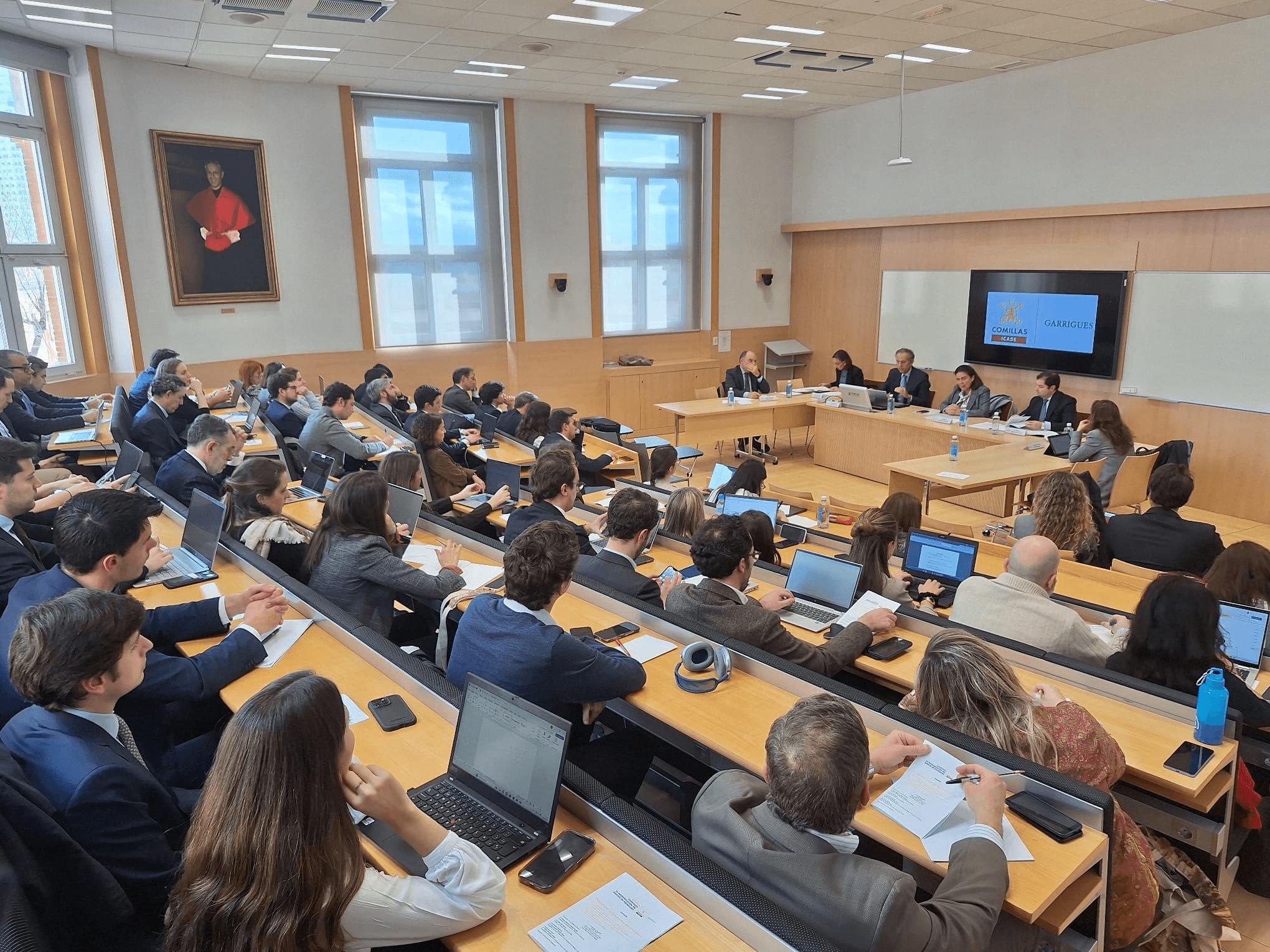 Una sala de conferencias llena de personas sentadas frente a una mesa con oradores.