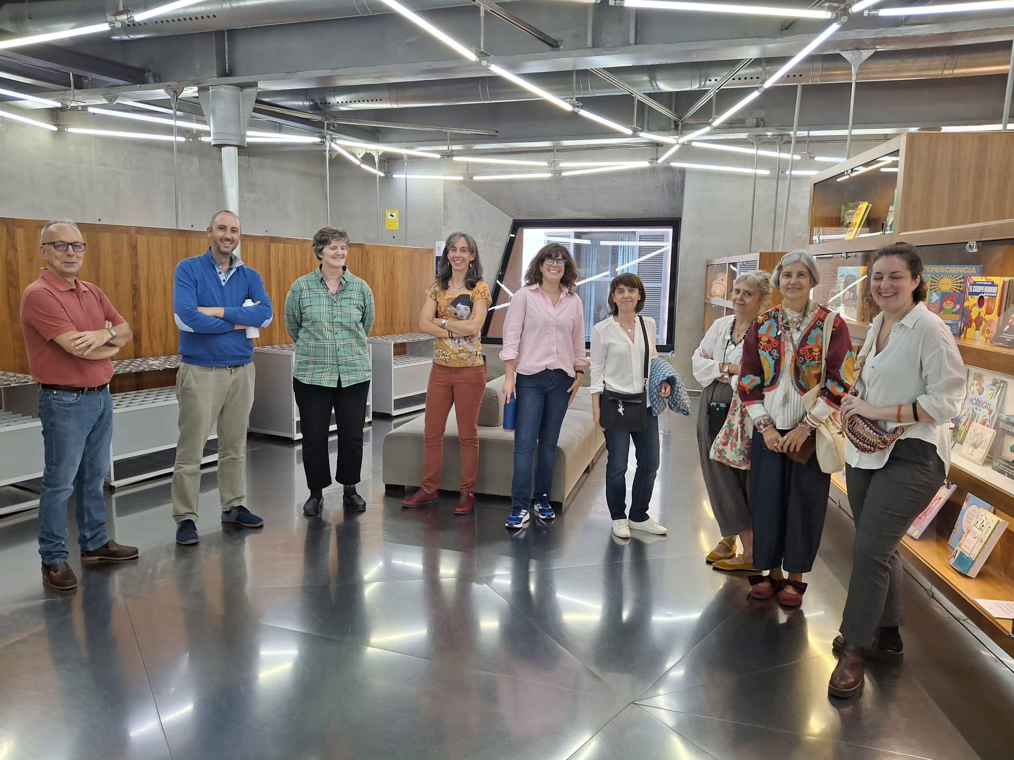 Un grupo de personas sonríe en una biblioteca moderna con estanterías de libros.