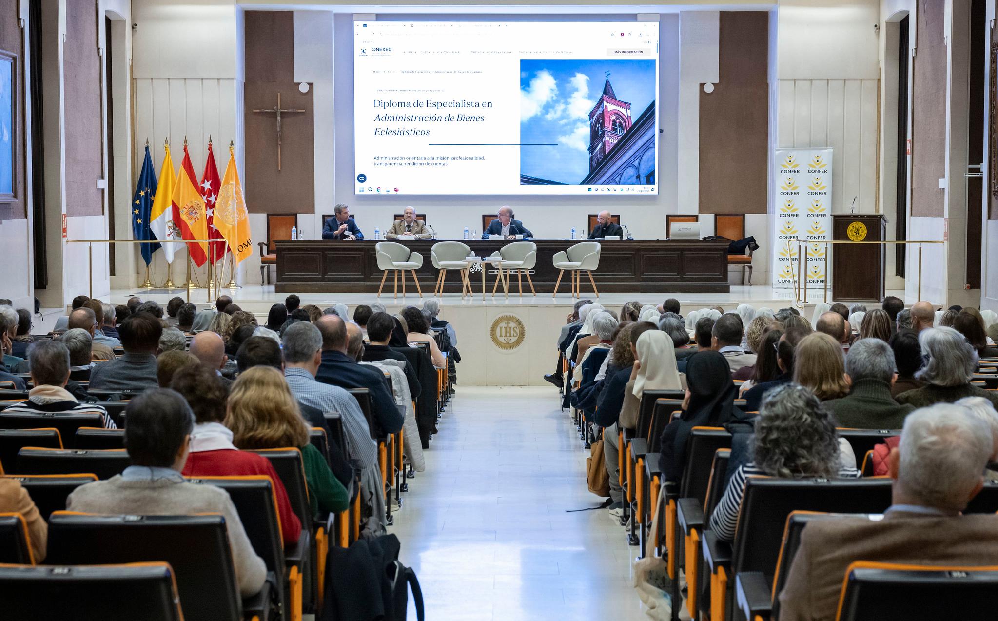 Una conferencia con un auditorio lleno de personas escuchando a varios ponentes en el escenario.