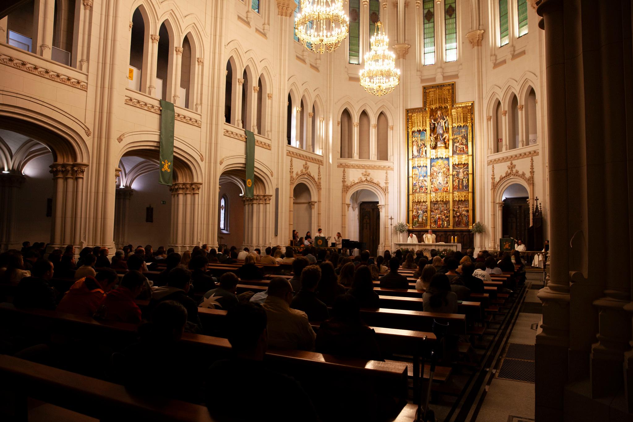 Una congregación asiste a un servicio religioso en una iglesia iluminada y ornamentada.