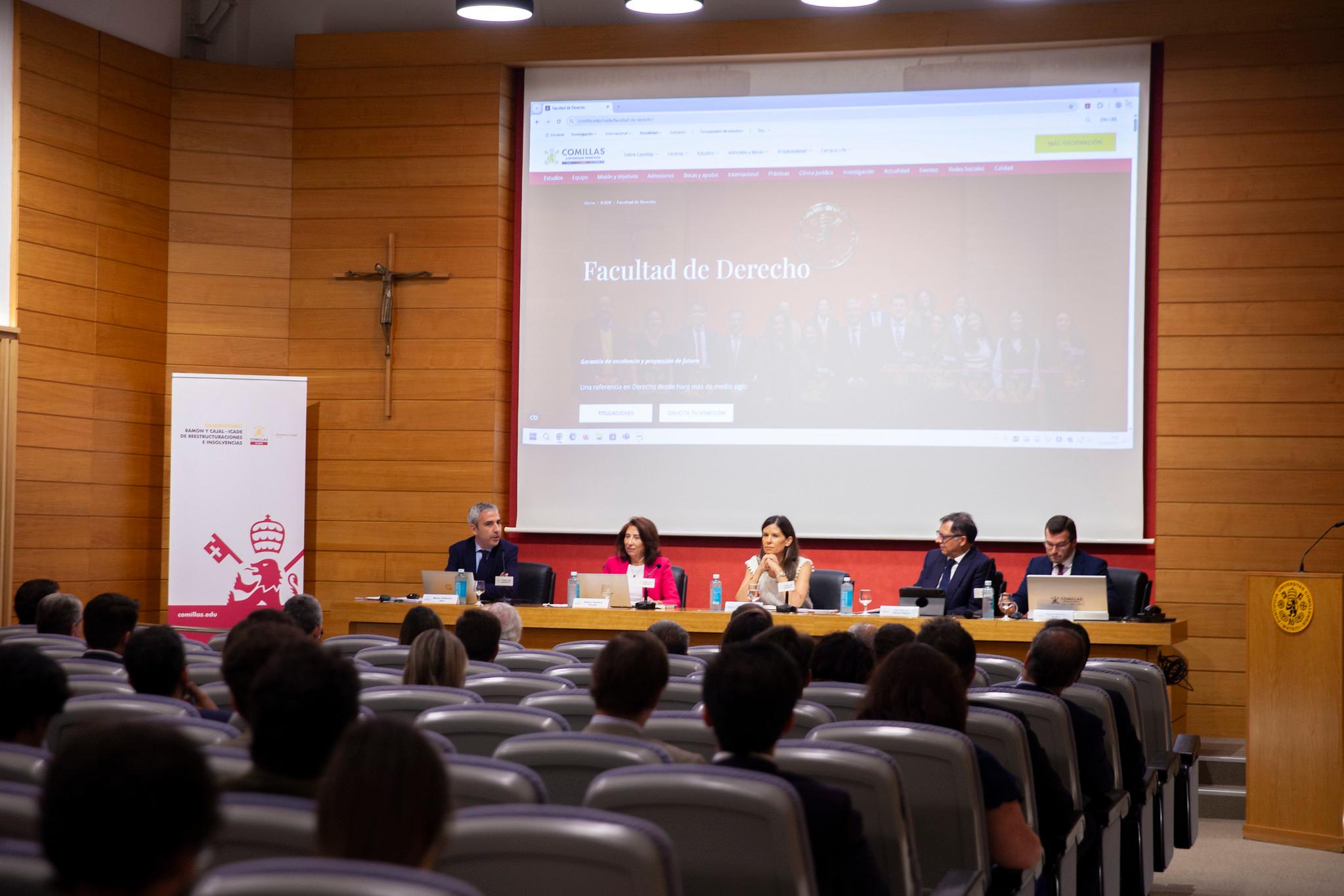 Una mesa redonda en la Facultad de Derecho con varios ponentes y asistentes en un auditorio.