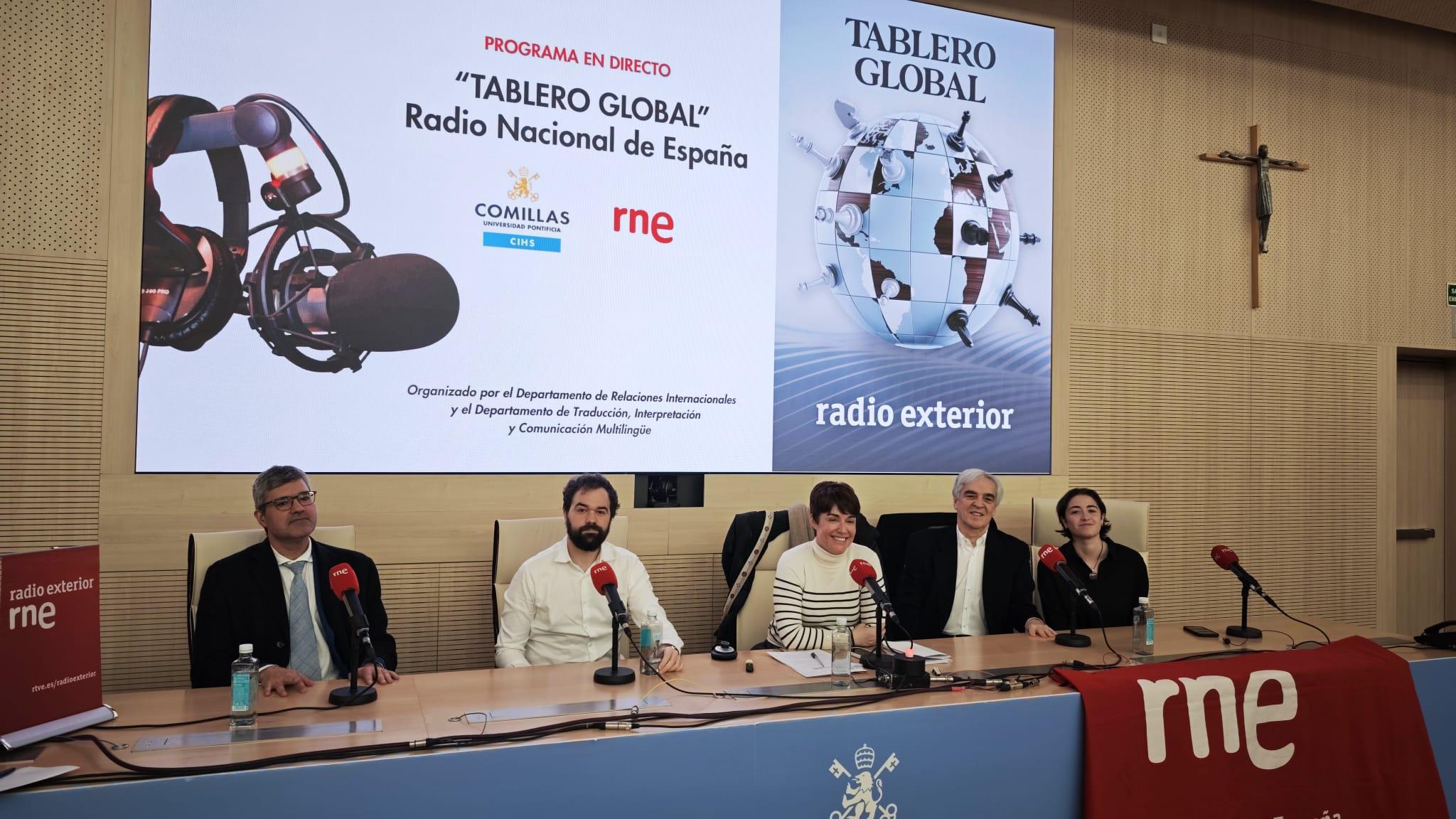 Una mesa redonda en un evento de Radio Nacional de España con cinco panelistas y decoraciones relacionadas con la radio.