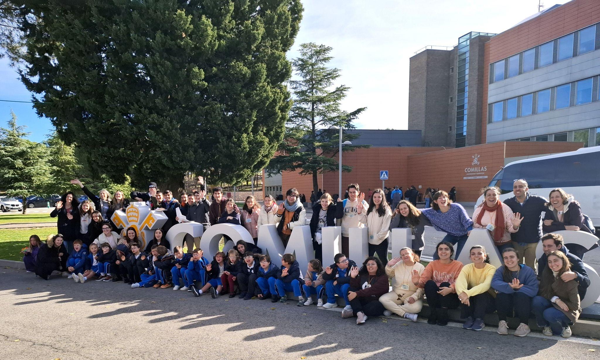 Grupo de personas posando frente a un edificio con un gran letrero que dice 'Comillas'.