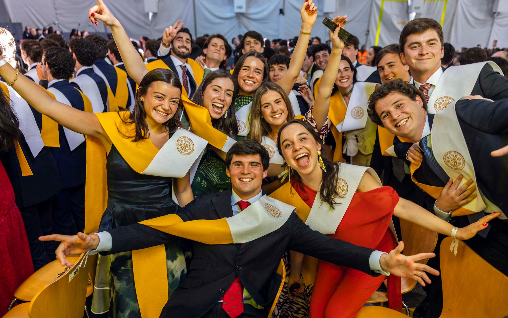 Grupo de estudiantes emocionados celebrando su graduación en un ambiente festivo.
