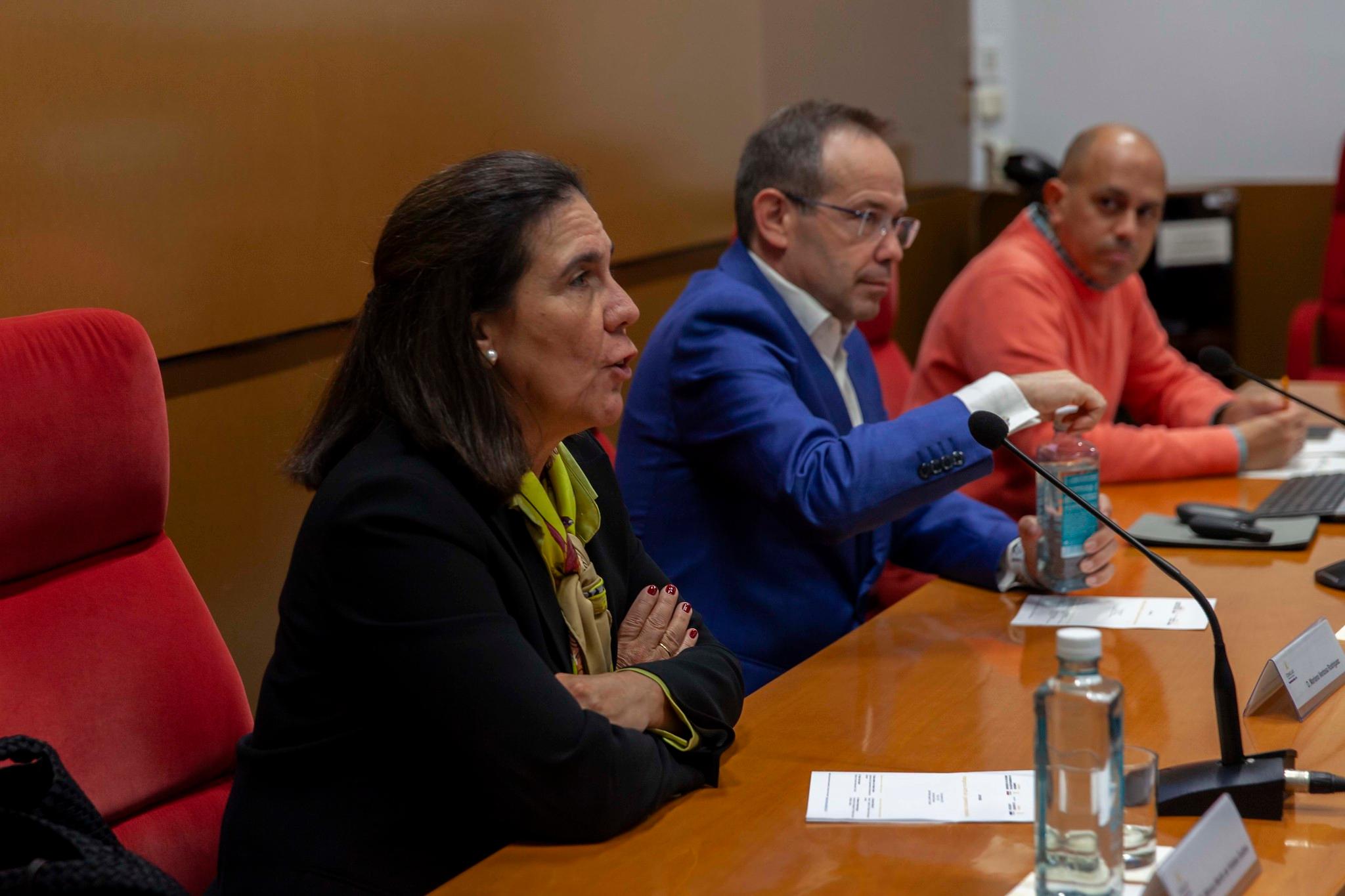 Three individuals engaged in a panel discussion in a conference room.