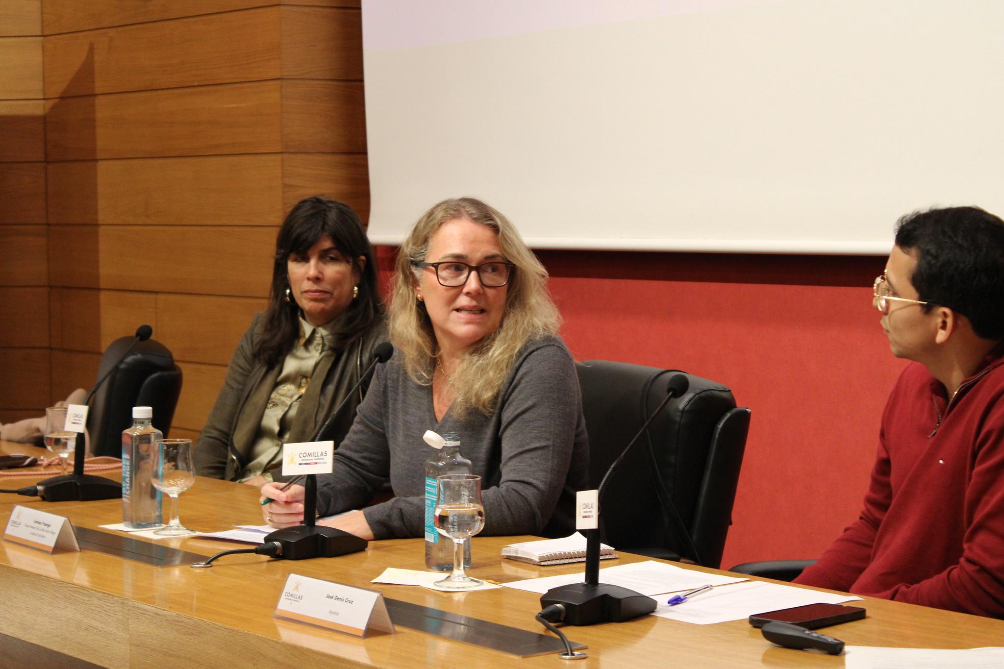 Tres personas participan en un panel de discusión en un evento académico o profesional.