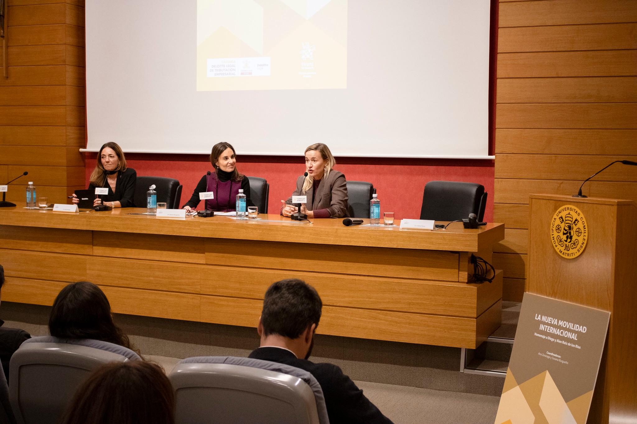 Cuatro mujeres están sentadas en un panel de discusión dentro de una sala de conferencias, frente a una audiencia.