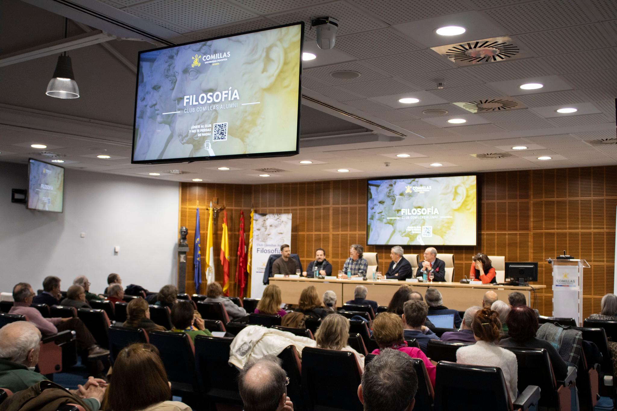 Una conferencia sobre filosofía con un panel de expertos y un público atento en una sala amplia.