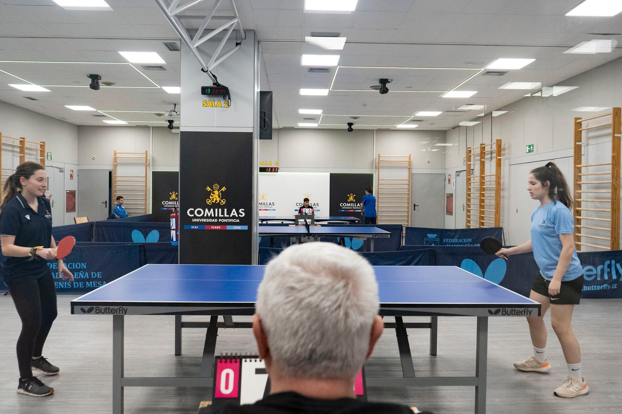 Dos jugadoras de tenis de mesa se preparan para un partido en una sala de deportes.