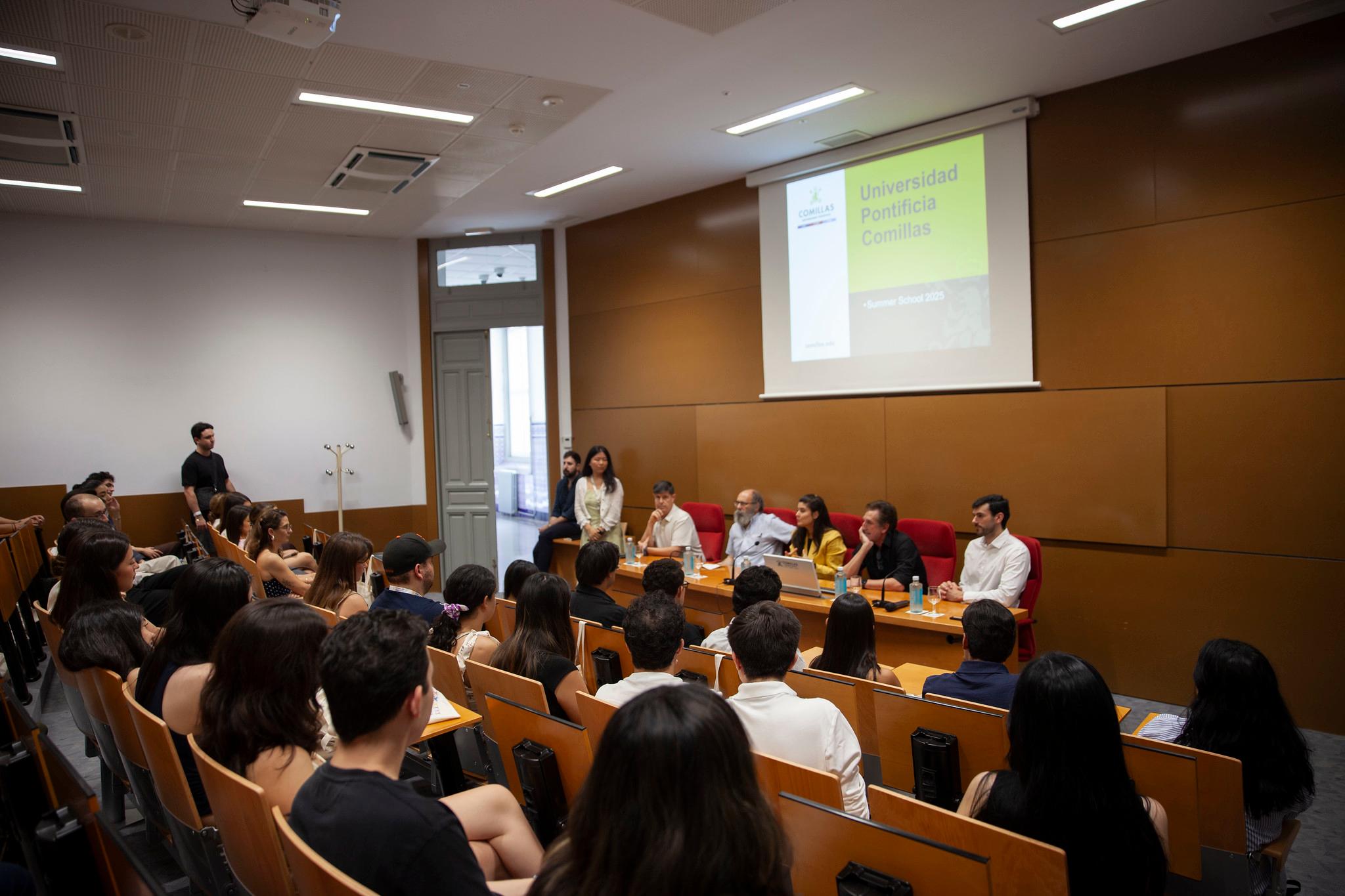 Un evento académico con un panel de oradores frente a una audiencia de estudiantes.