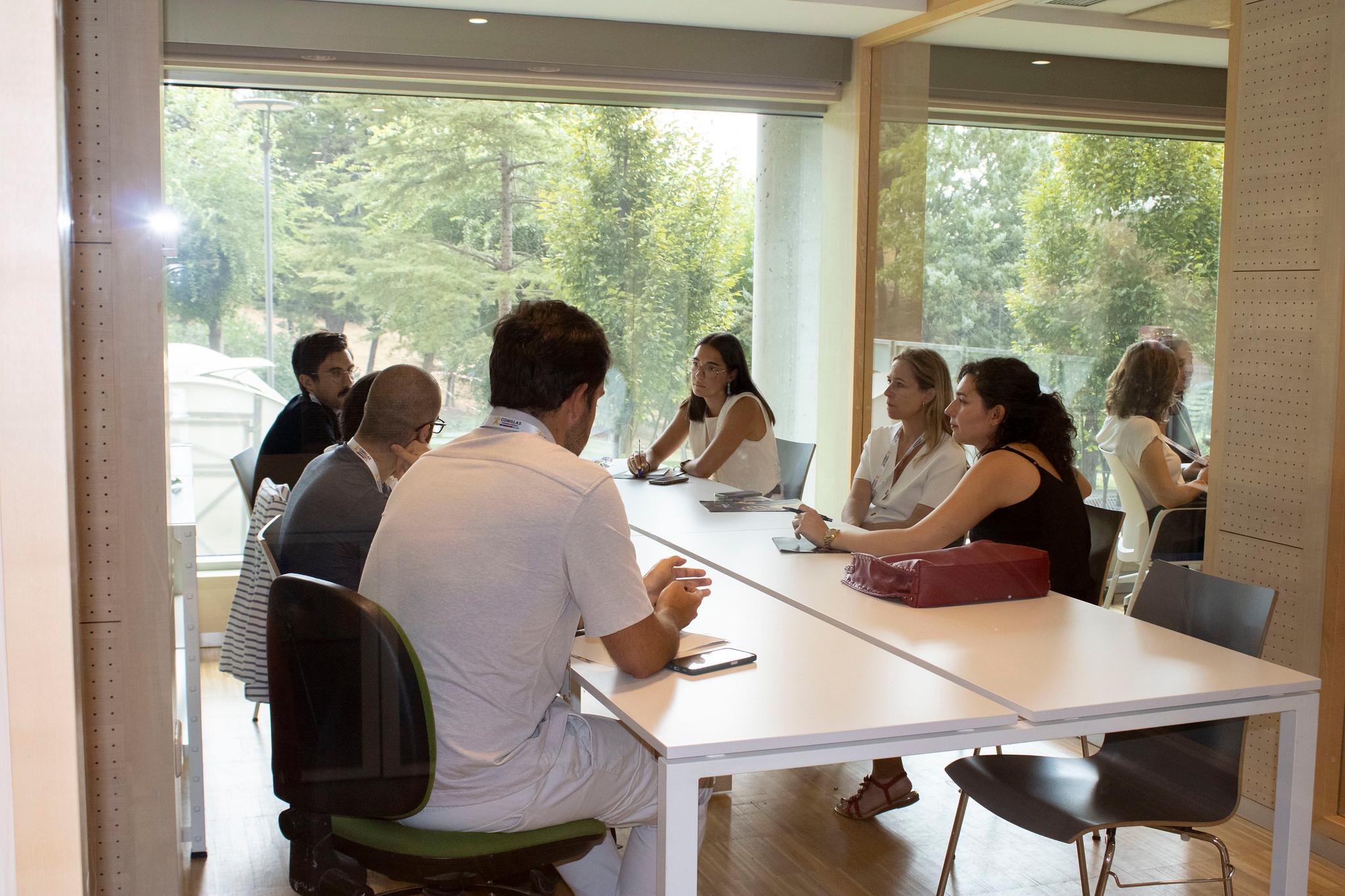 Un grupo de personas se reúne en una sala de conferencias iluminada por la luz natural.