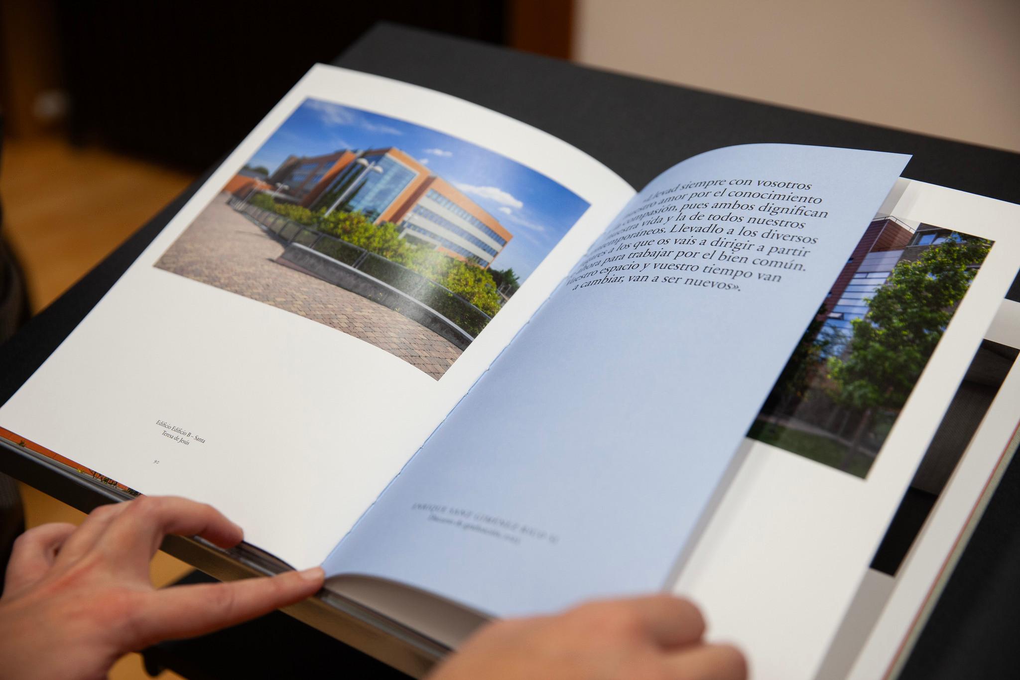 Una persona está hojeando un libro con imágenes de un edificio moderno.